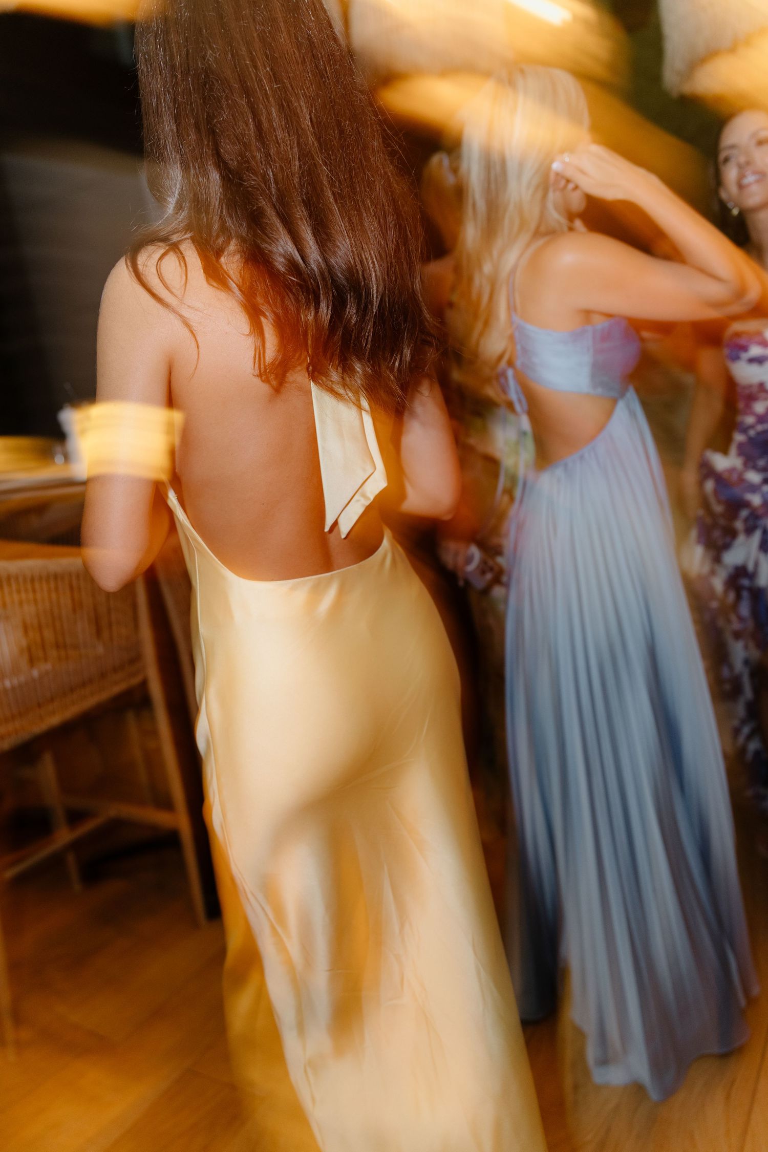 Candid dance floor scene with people in flowy dresses in yellow and blue tones.