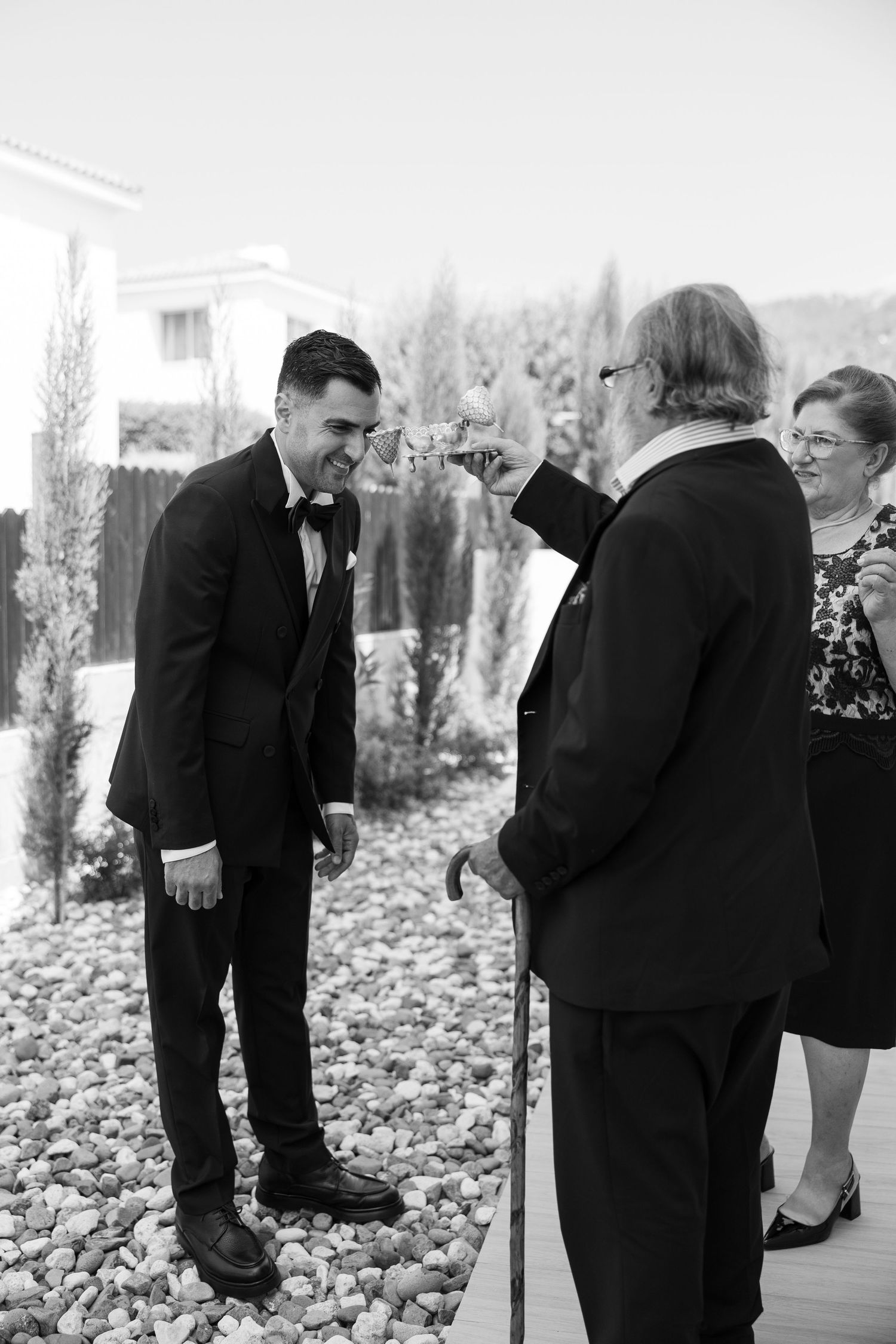 Black and white photo of wedding ceremony with officiant and groom sharing a joyful moment on outdoor deck.