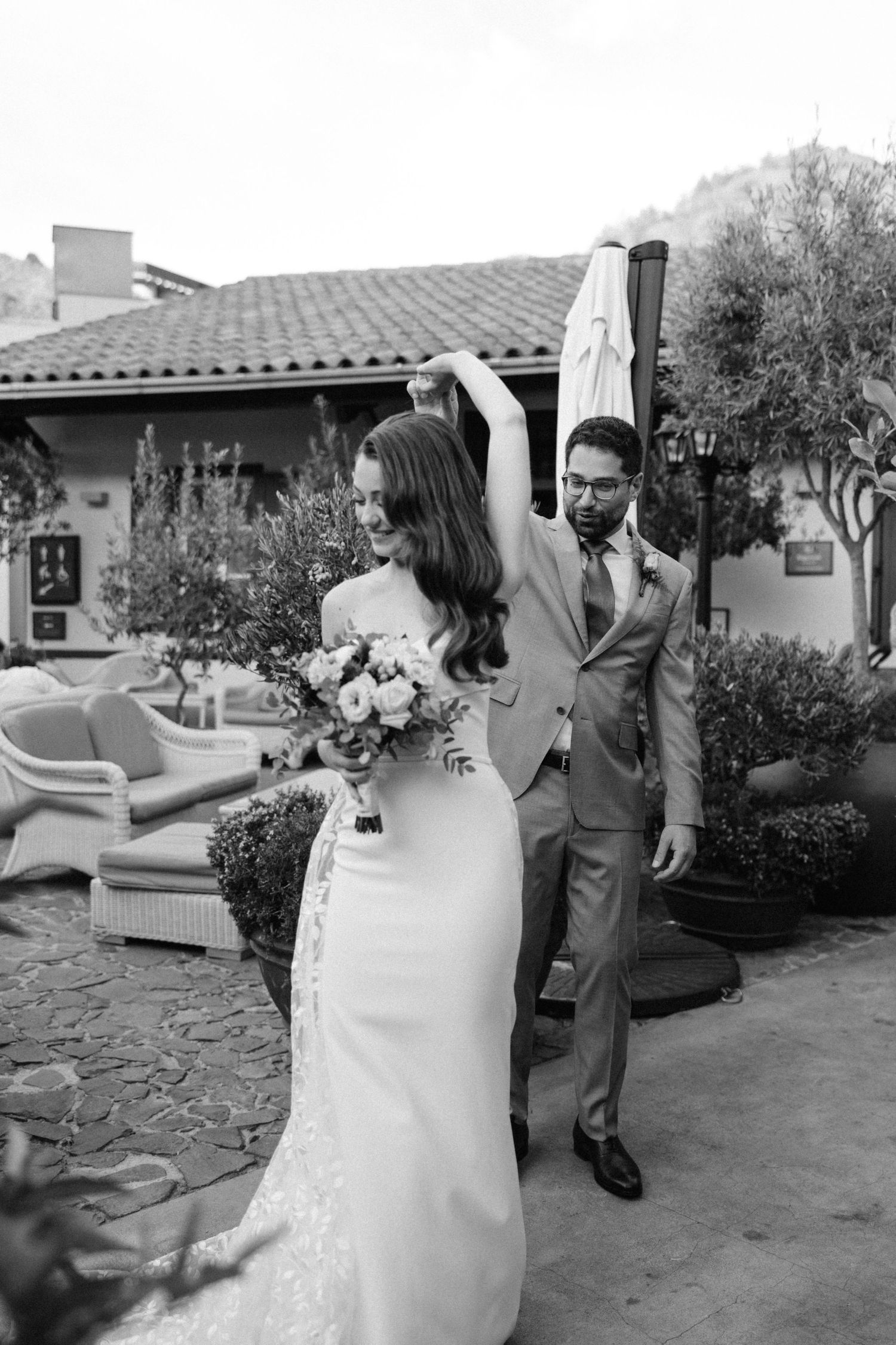 Black and white photo of couple during first look in Mediterranean-style courtyard.