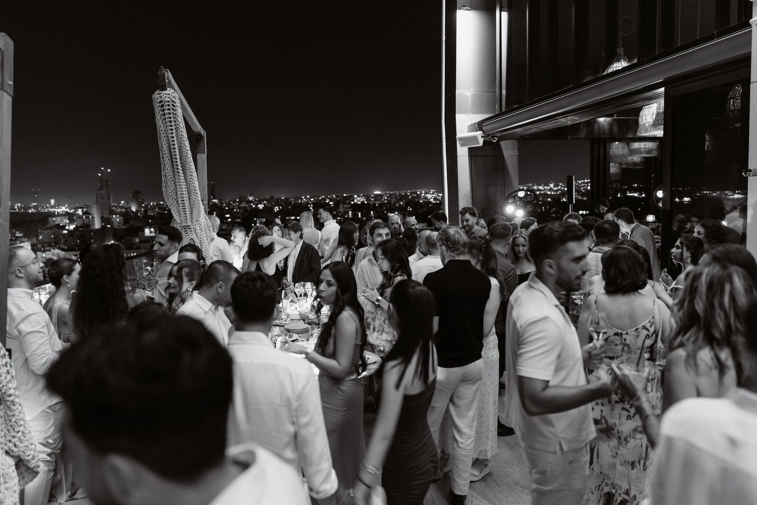 A large crowd of people wearing white shirts wave their hands in the air during what appears to be a group celebration.