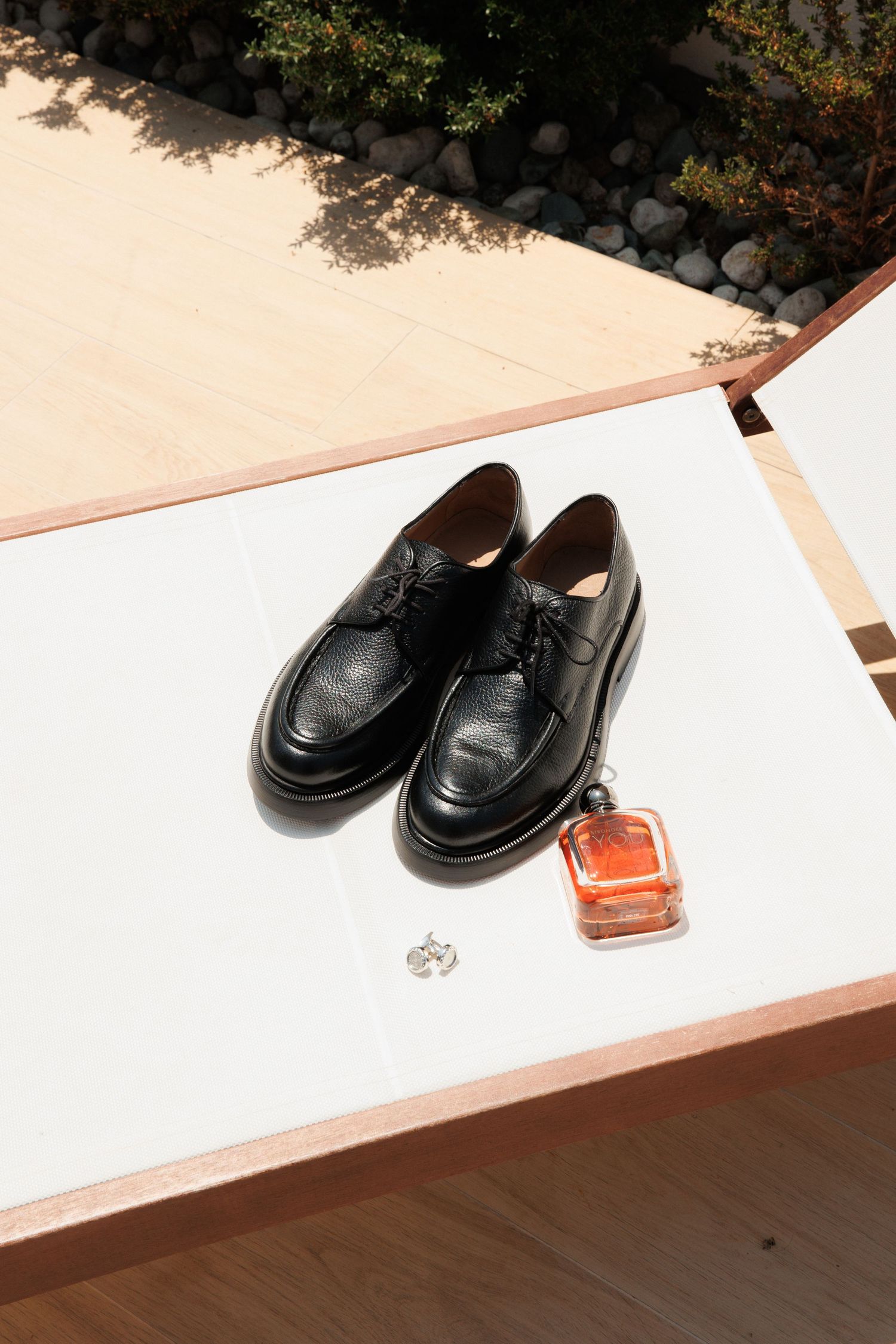 Black leather penny loafers displayed on a white surface with some accessories visible in the frame.