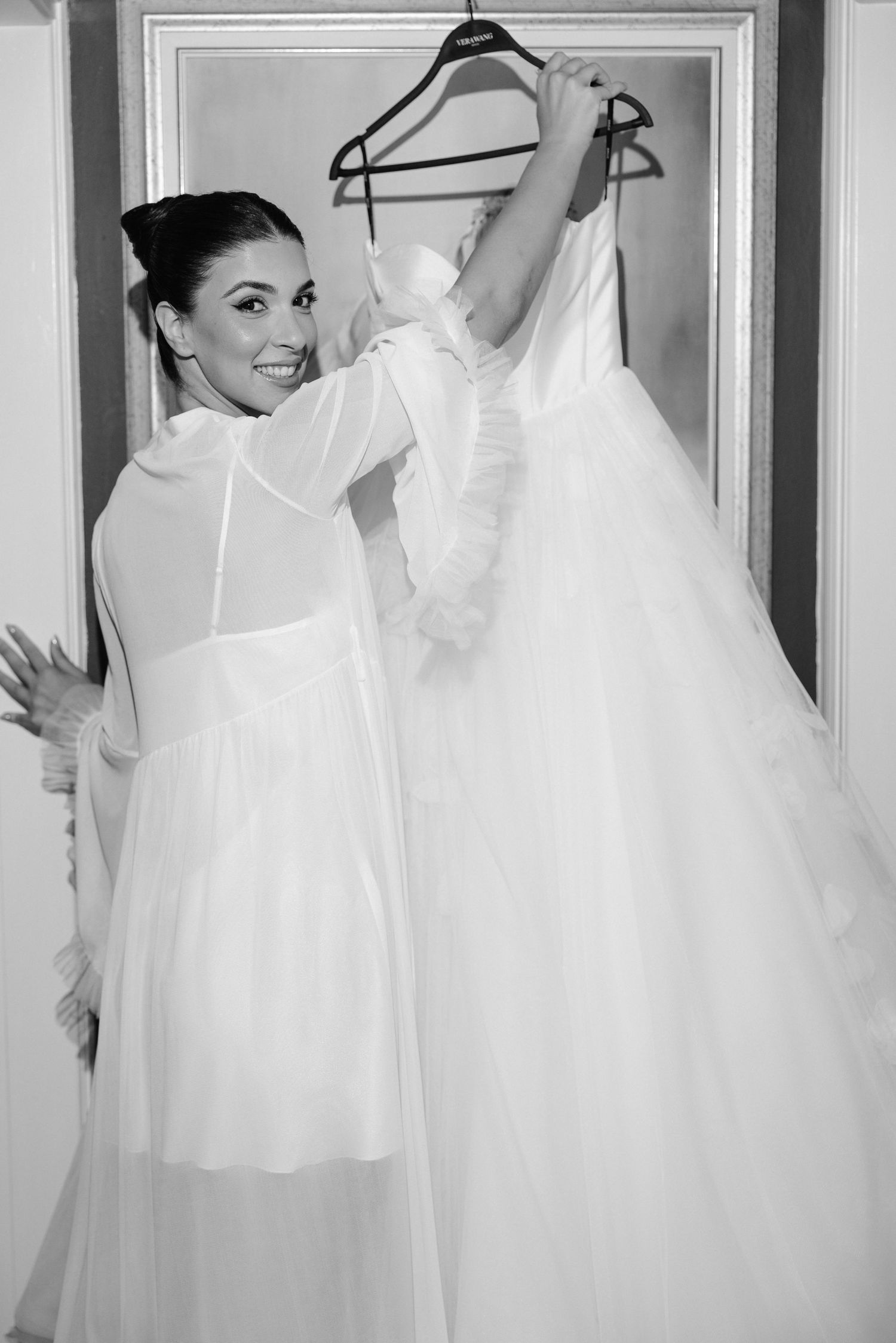 A series of white wedding dresses hanging on display in a bridal shop.