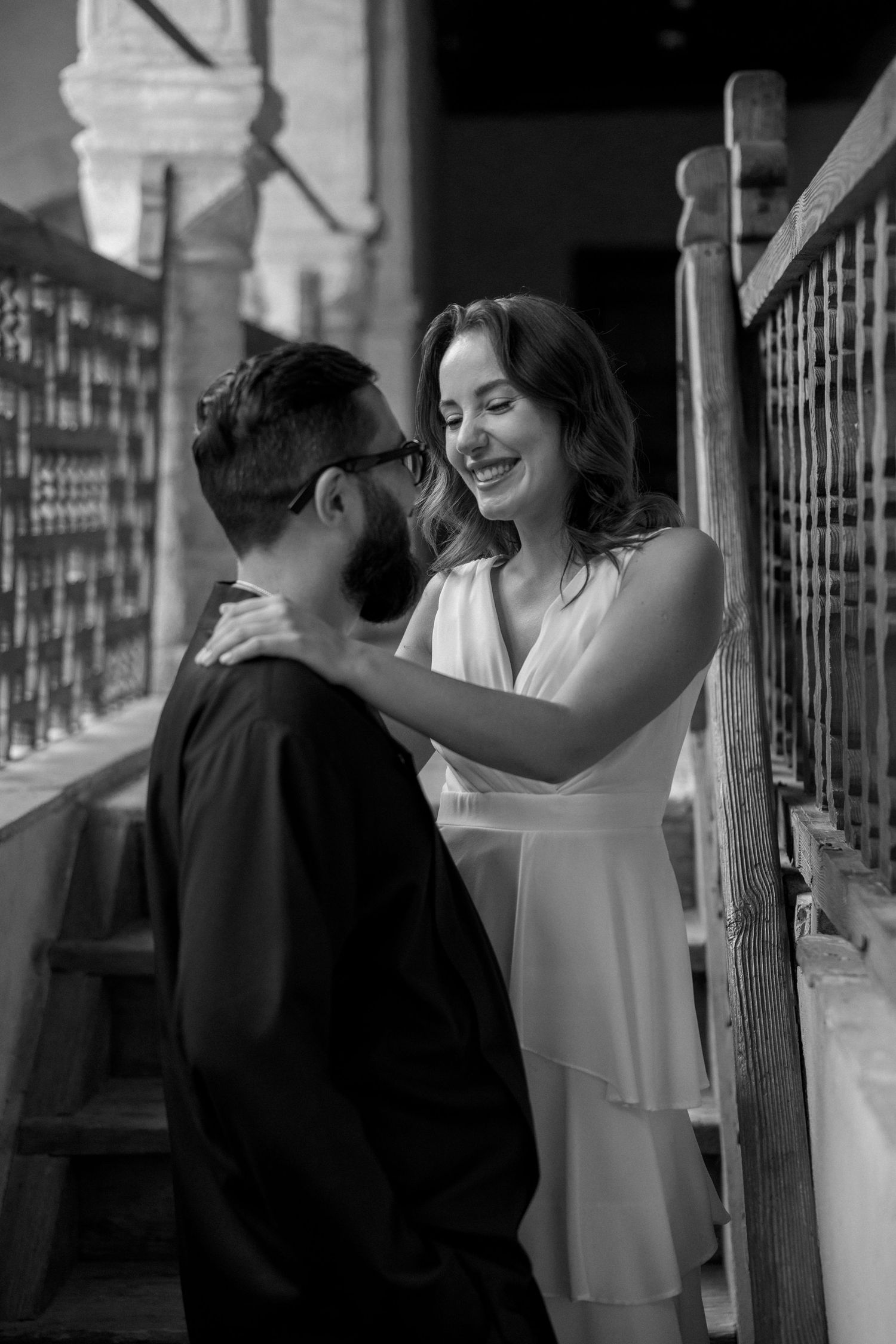 A black and white series of four photos showing a couple talking and interacting on a front porch.