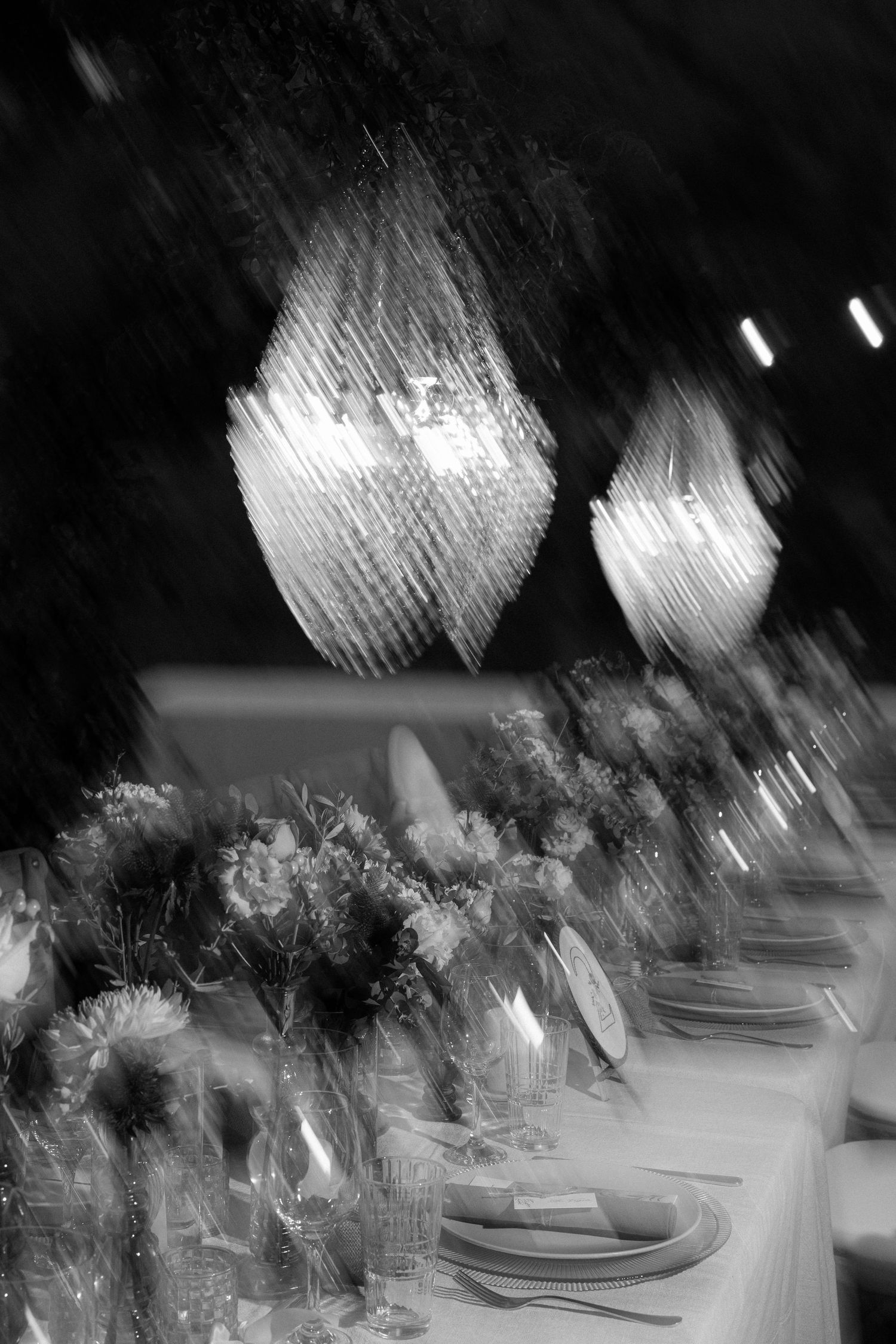 Artistic blurred shot of crystal chandeliers above formal dining table.