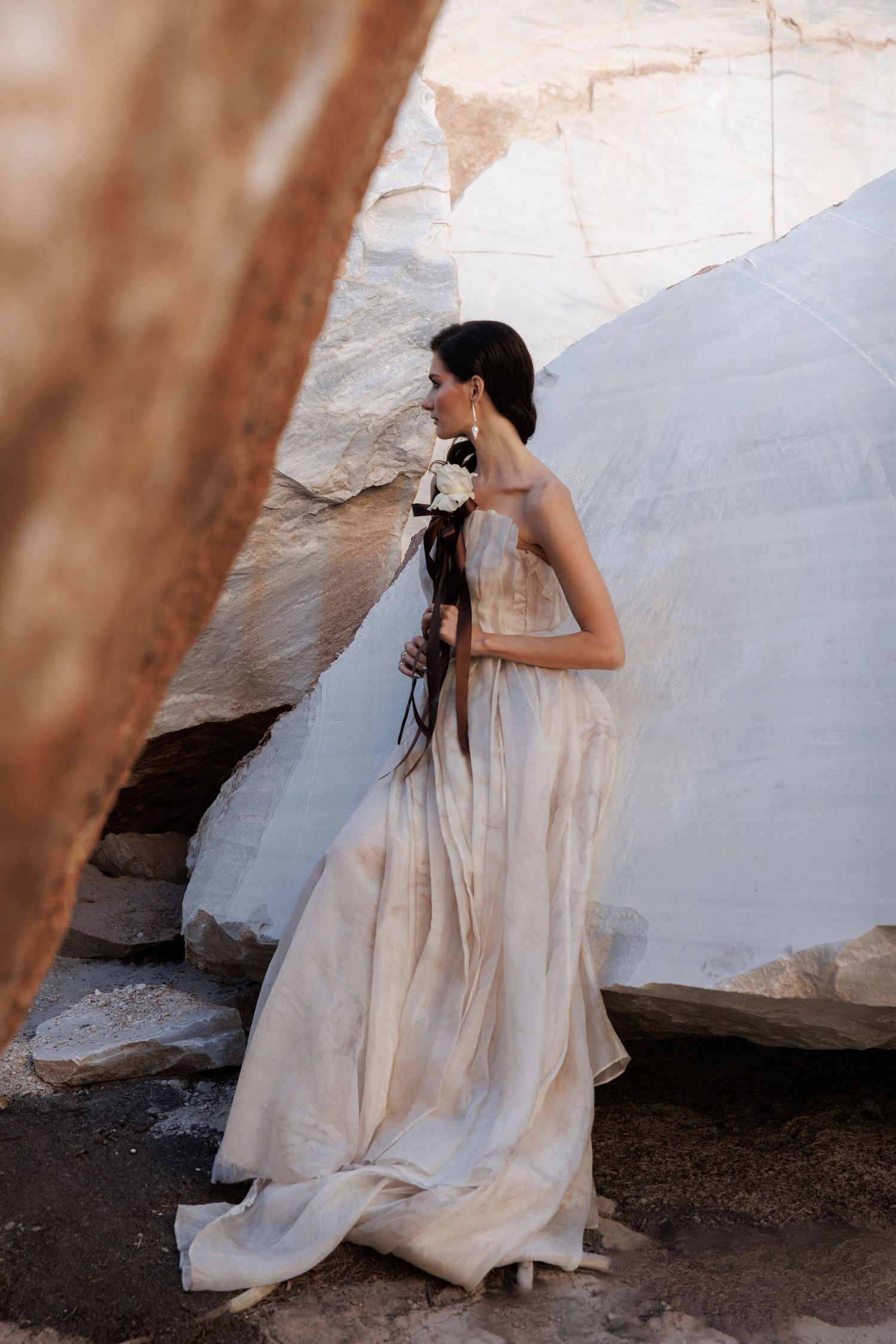 Elegant bridal portrait against white stone wall with minimalist bouquet.