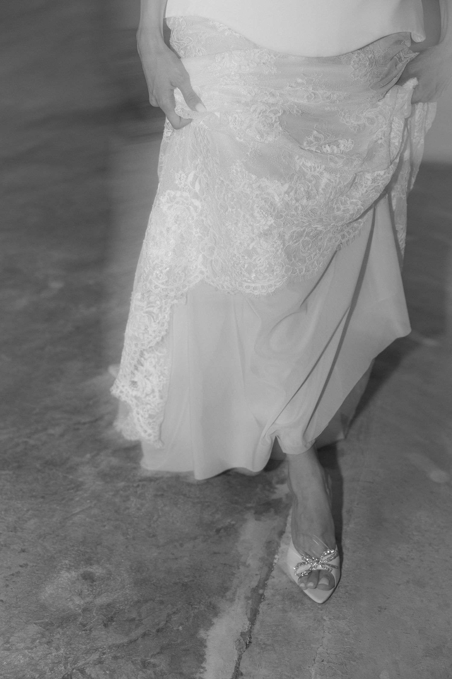 Close-up detail of a bride's lace wedding dress hem and sparkly shoe.