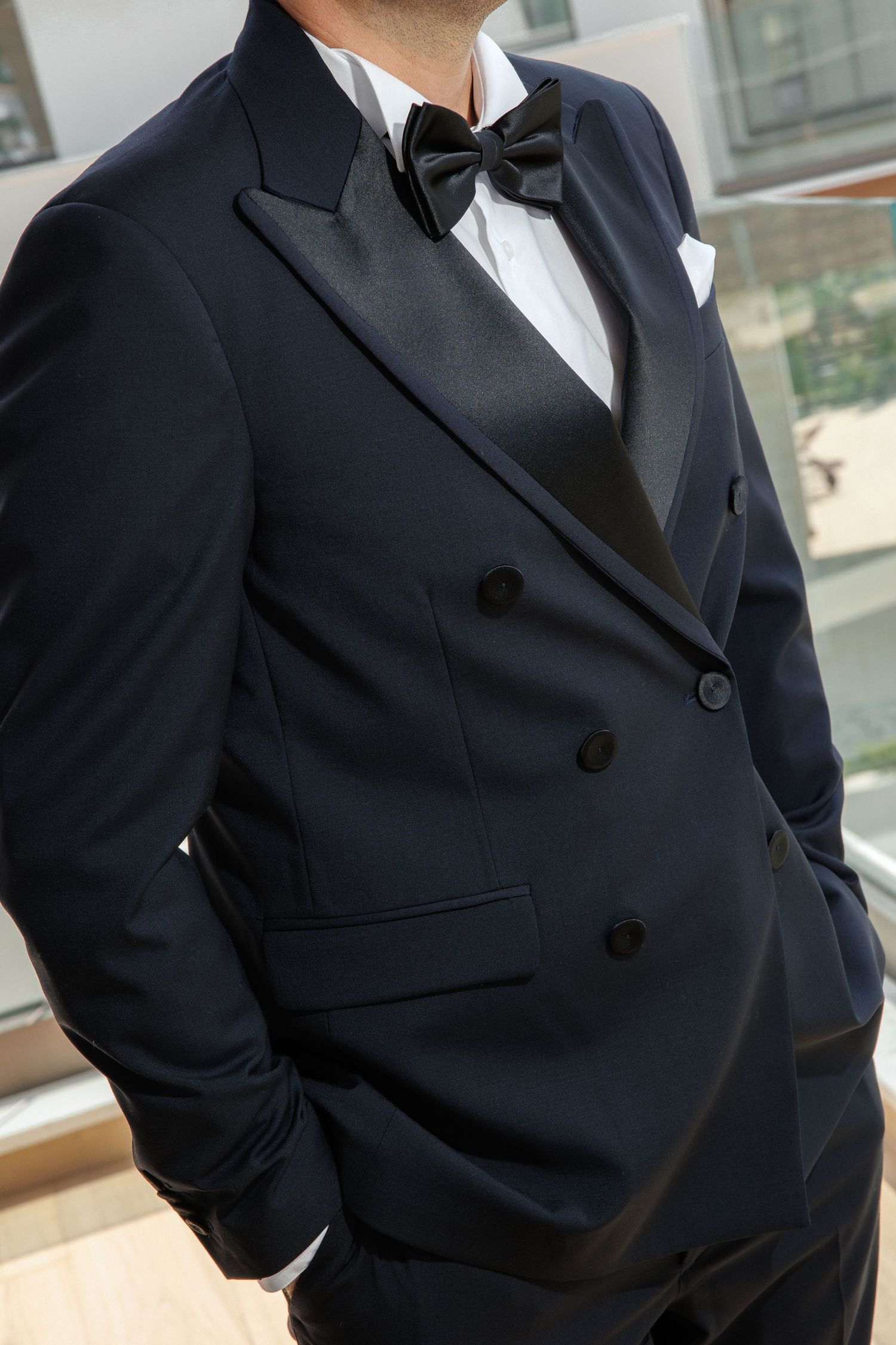 Close-up view of a classic black tuxedo jacket with bow tie and white dress shirt showing elegant formal attire details.