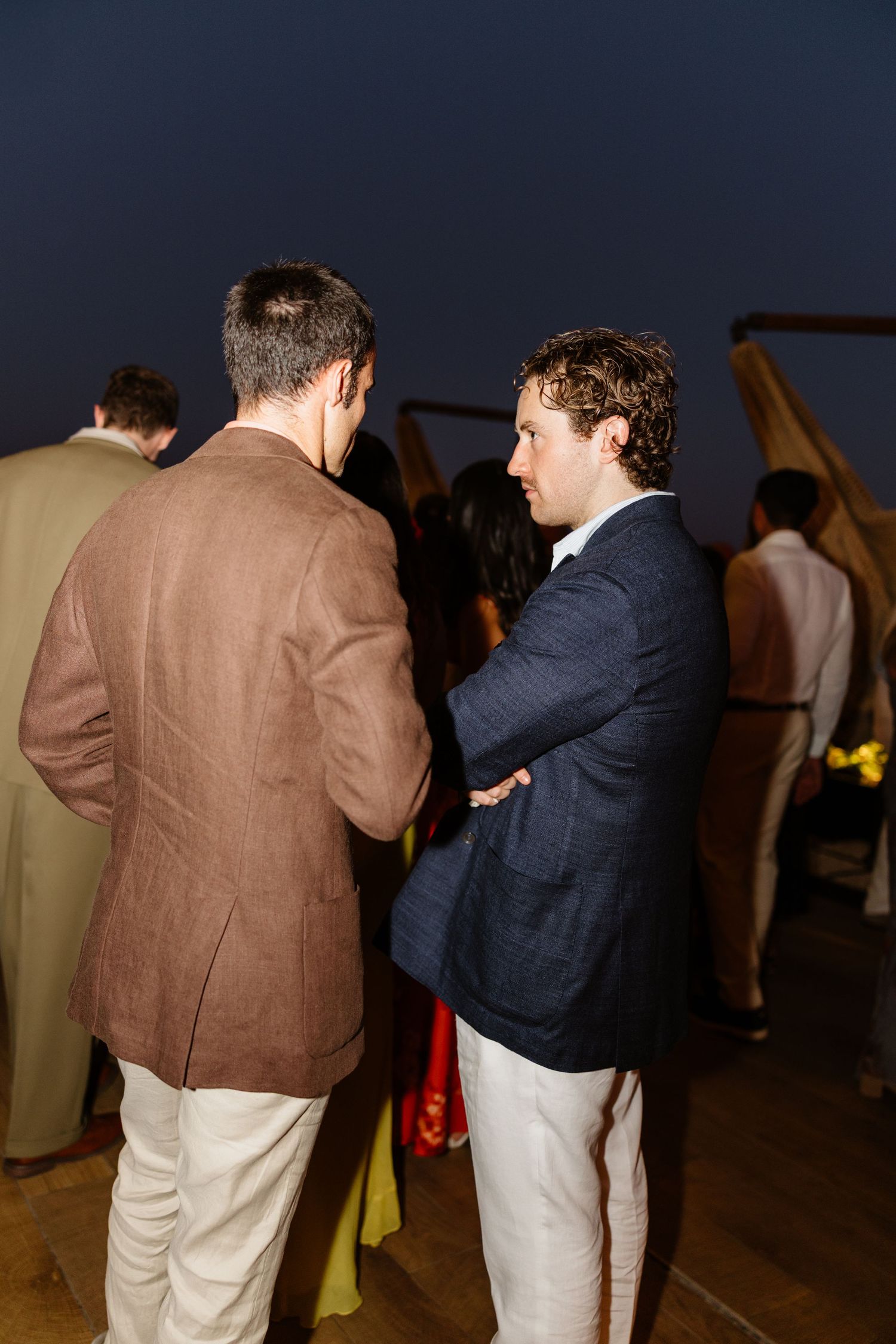 Two men in business attire having a conversation at an indoor event.
