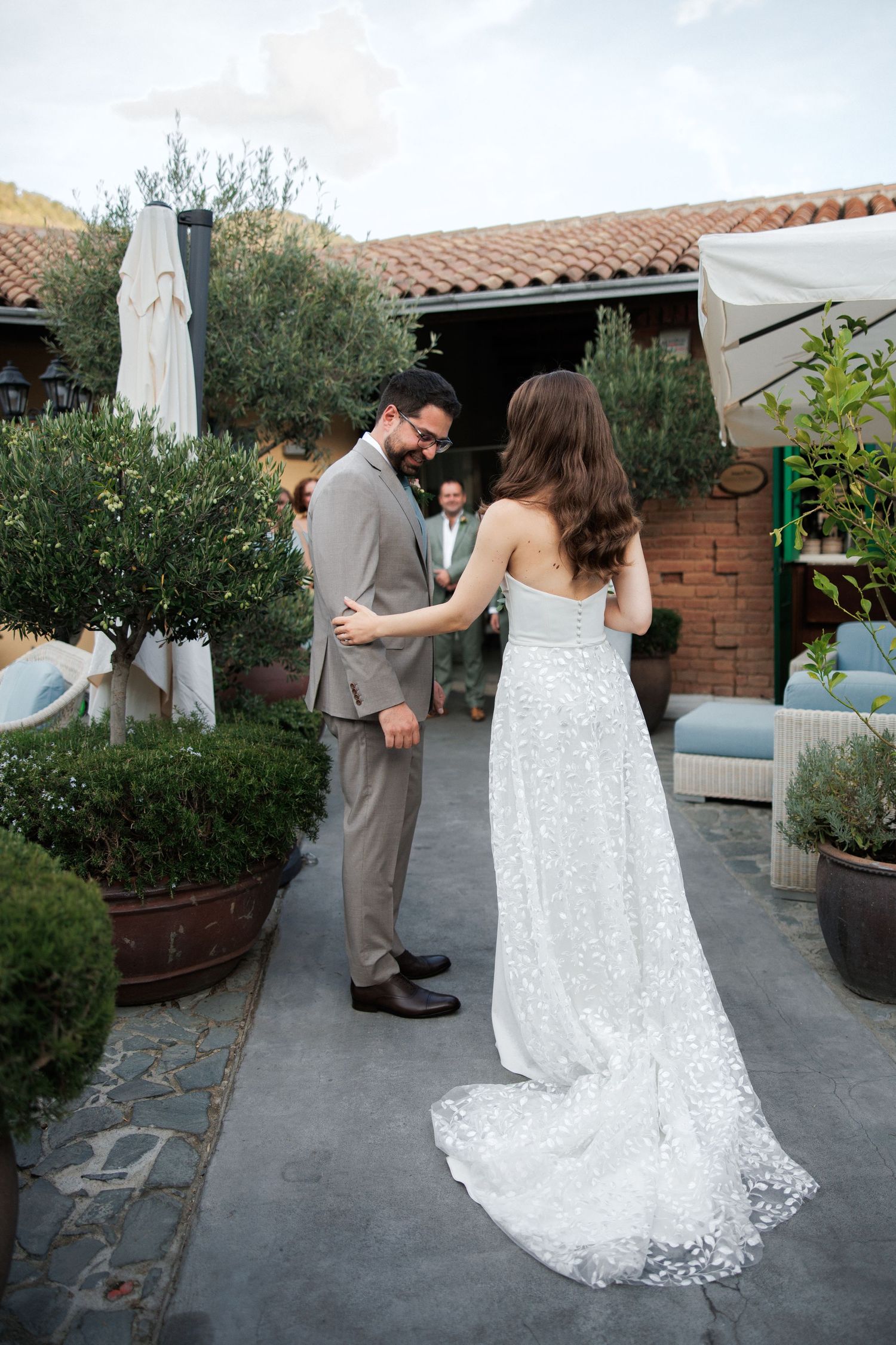 Couple sharing first look moment in garden courtyard with terracotta roof tiles.