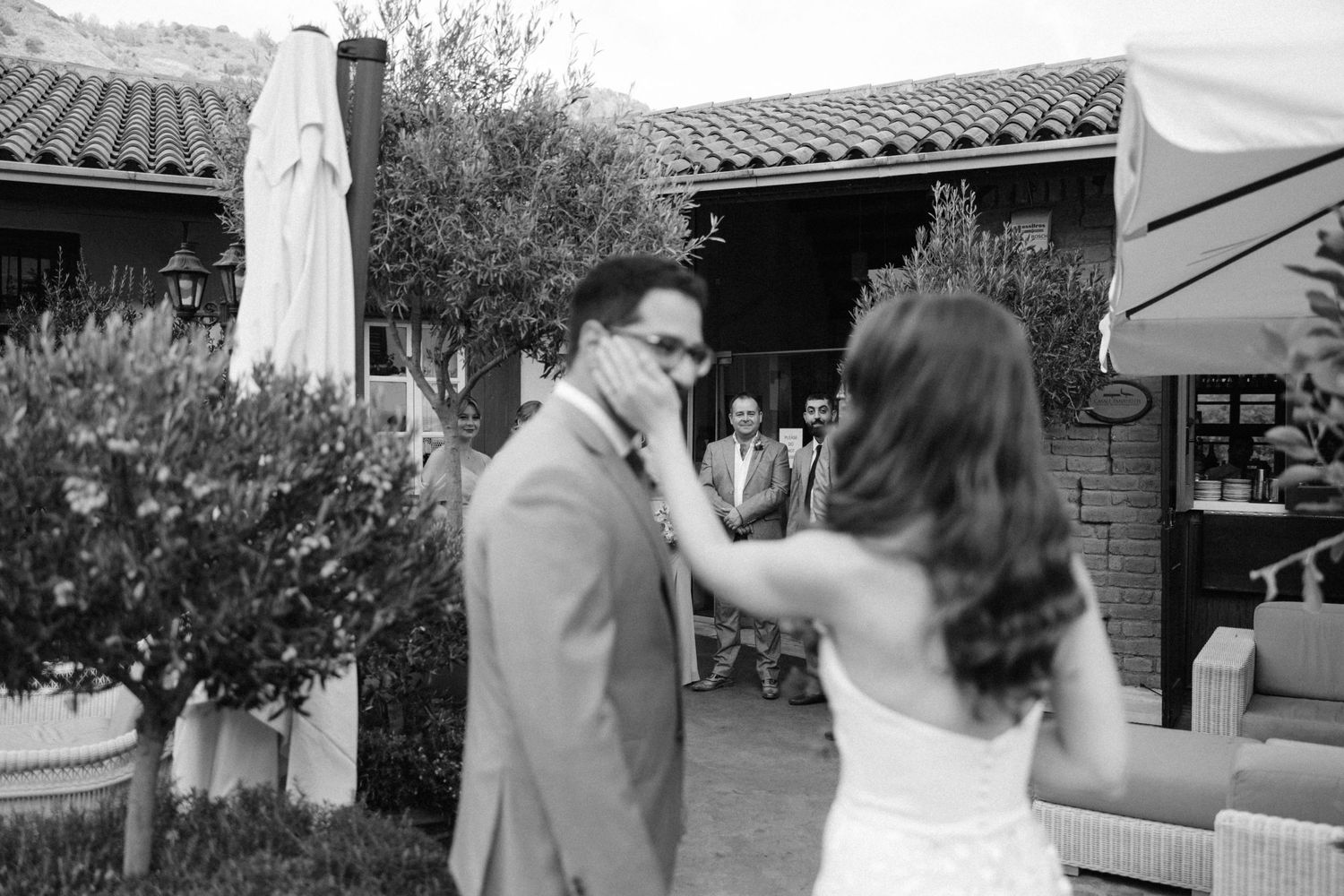 Black and white candid moment of couple's joyful first look in garden setting.