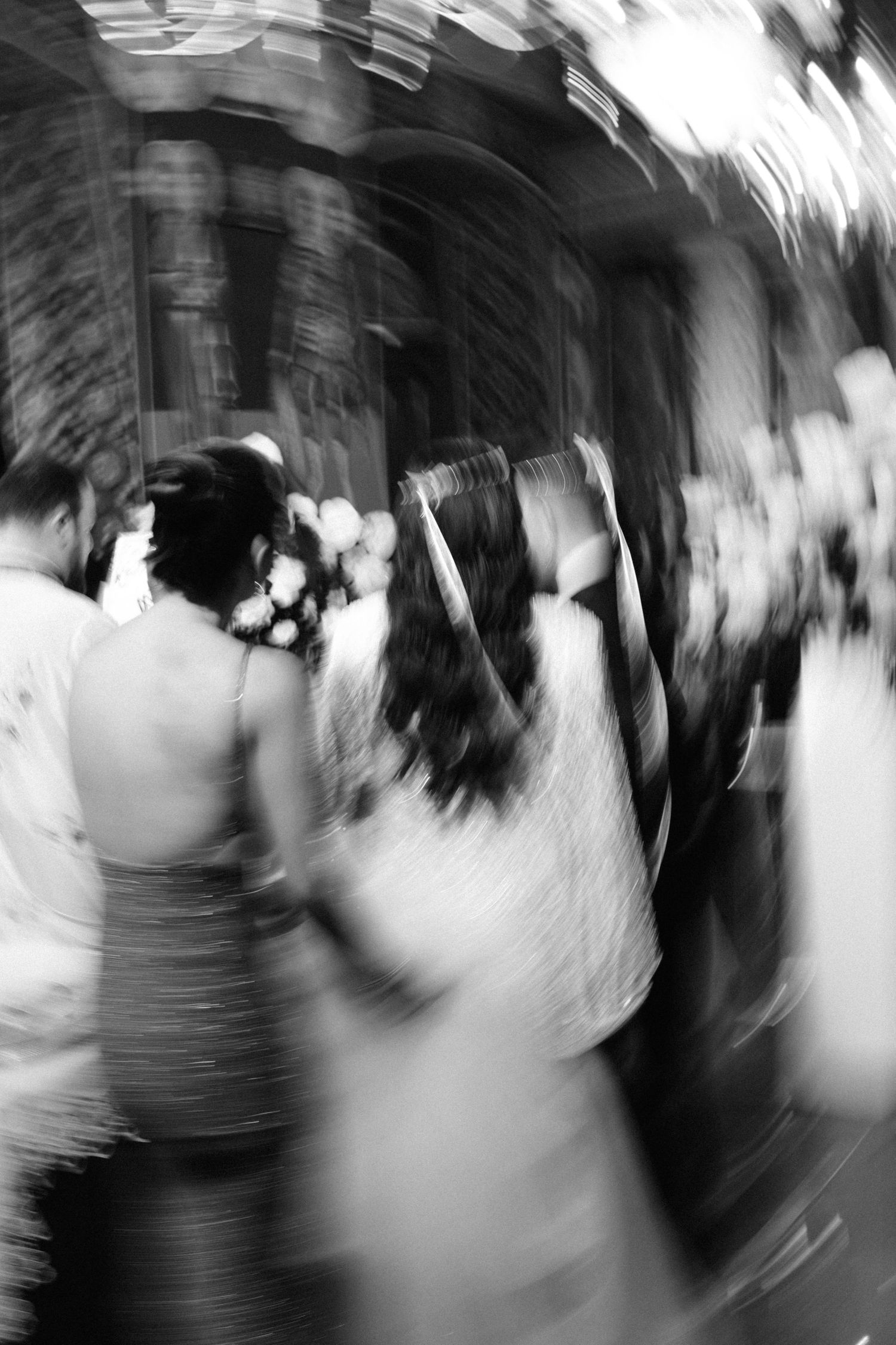 Blurred black and white photo of wedding guests celebrating at an outdoor ceremony.