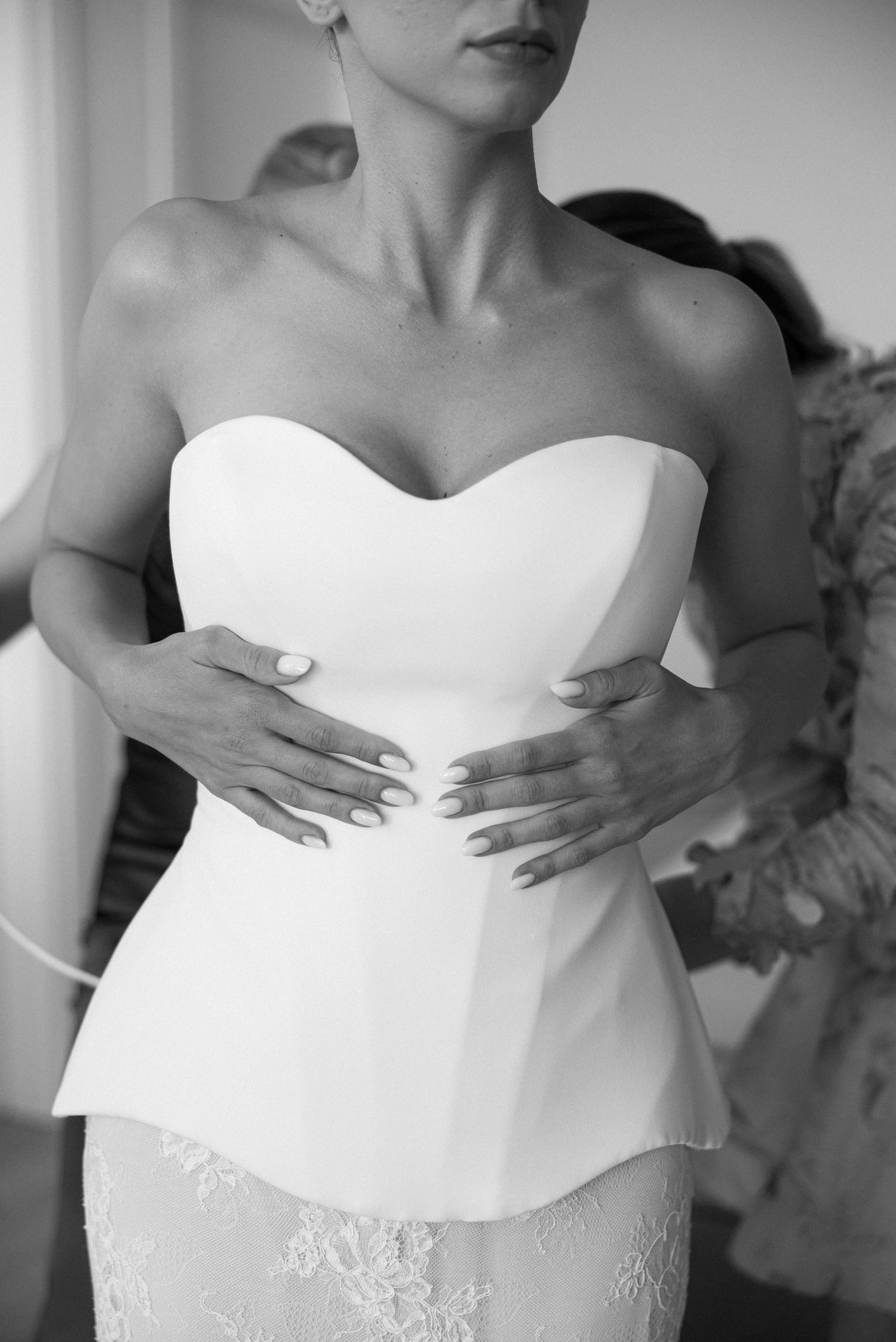 Close-up details of a white strapless wedding dress bodice with delicate lace embellishments.