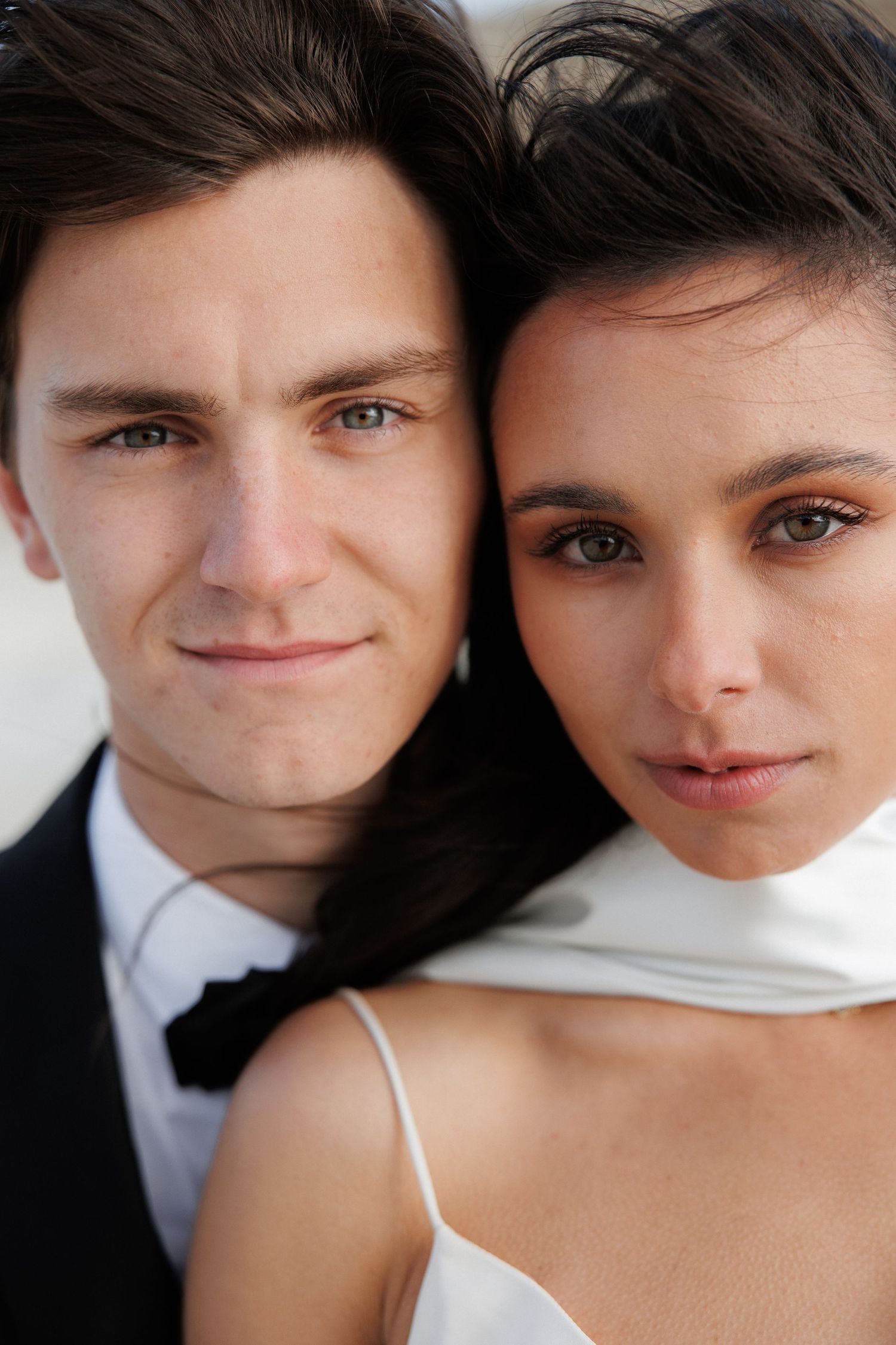 A romantic wedding portrait shows a couple in formal attire with intimate close-up composition.