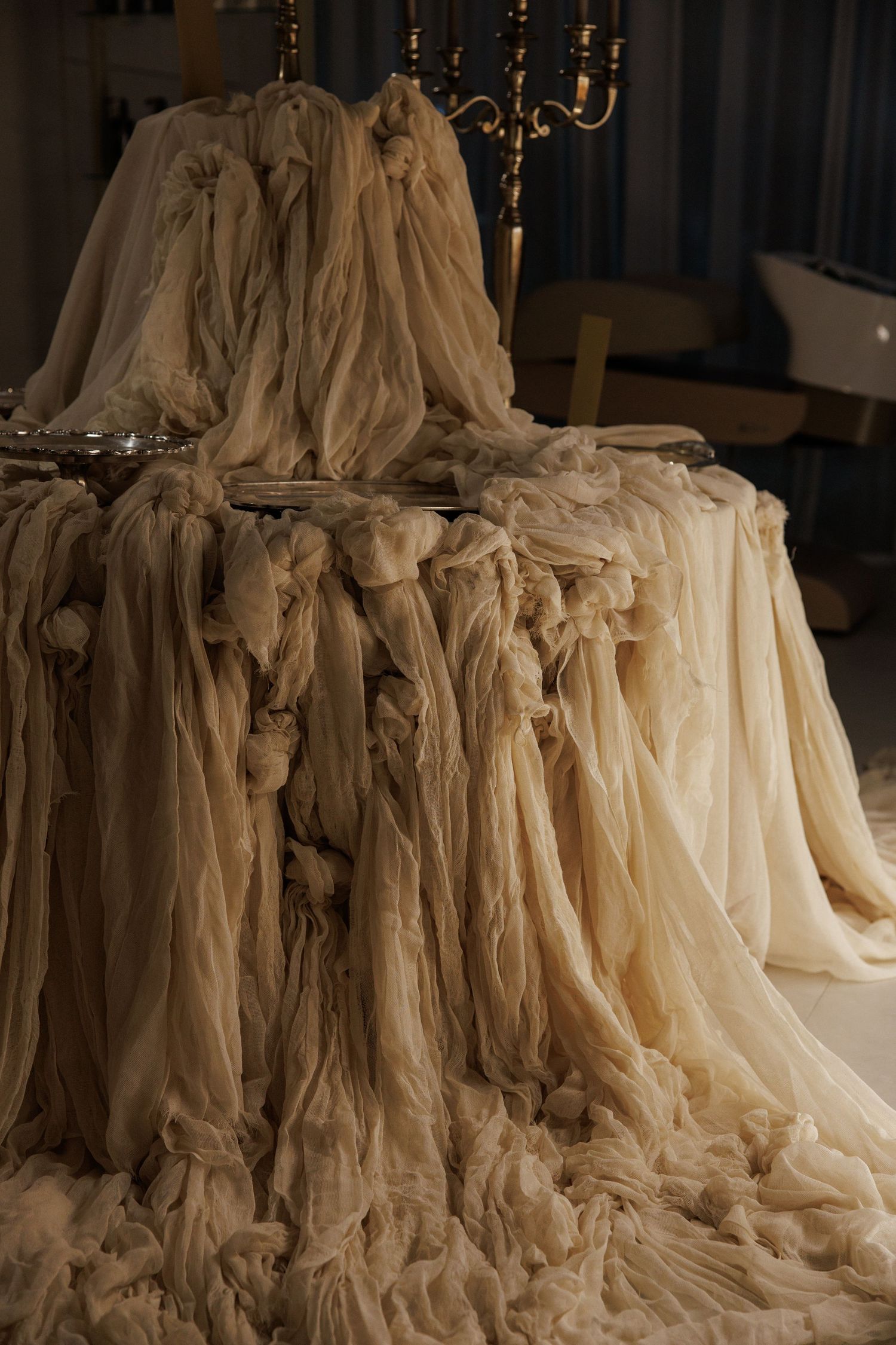 Vintage-inspired cream colored gowns draped dramatically with chandelier in background.