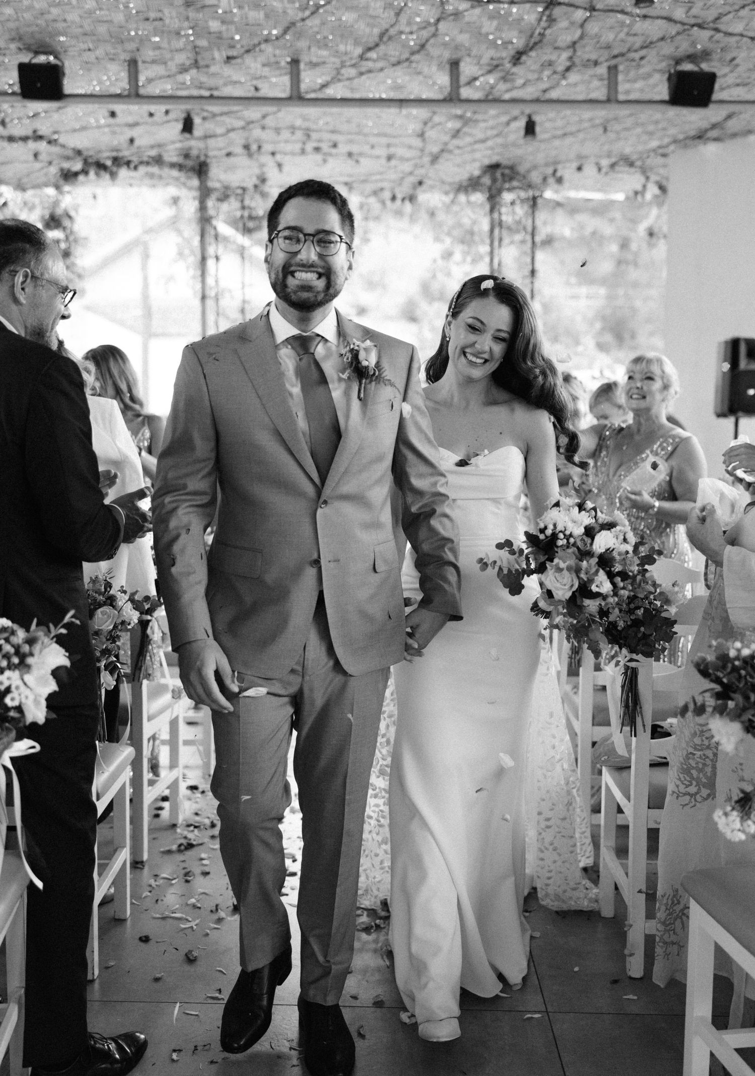 Black and white photo of newlyweds walking down aisle after ceremony.