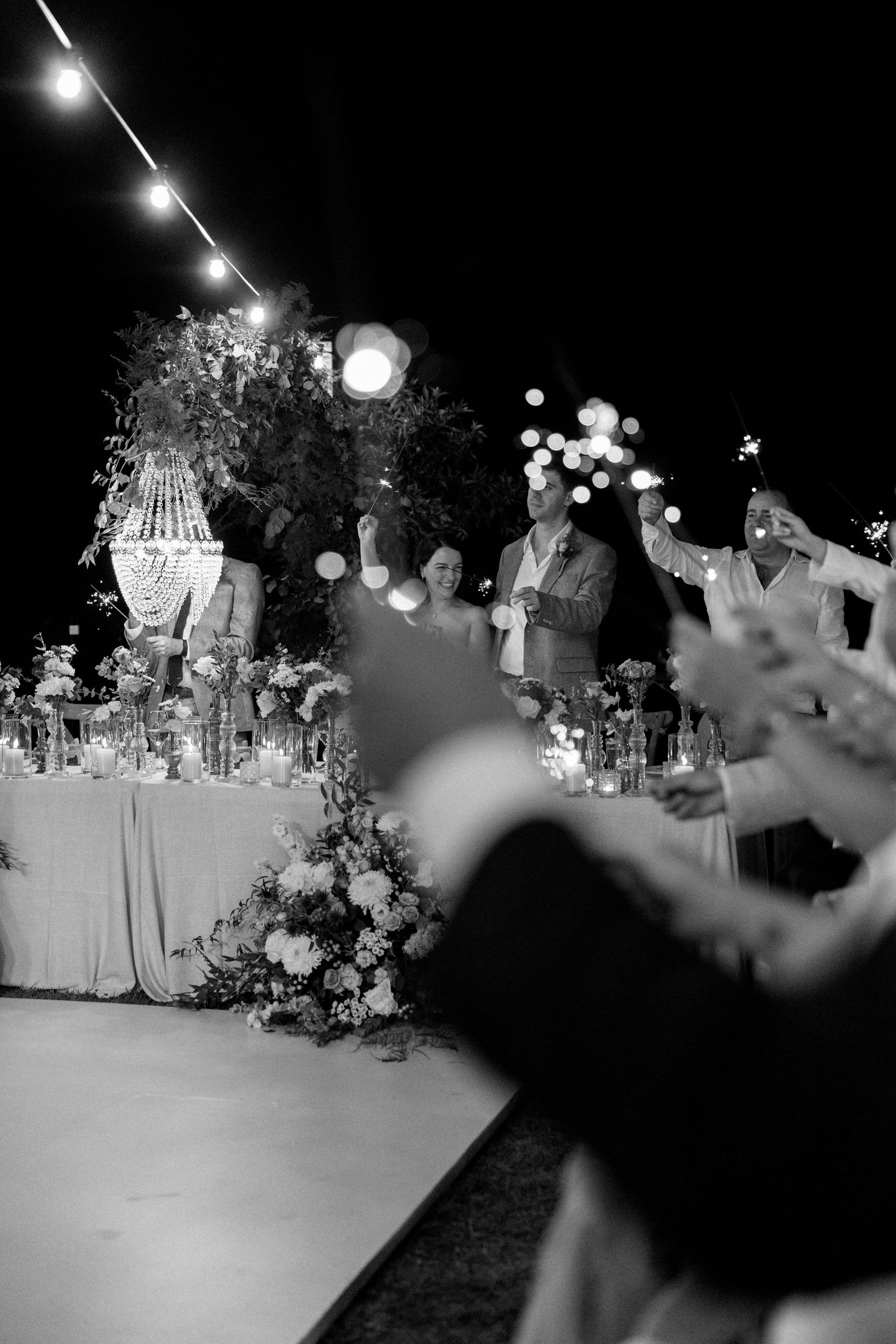 Evening reception setup with hanging lights and crystal chandeliers creating magical ambiance.
