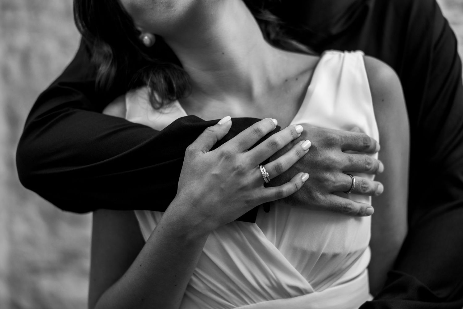 Close up black and white photo showing an intimate embrace between two people with one wearing a white dress.