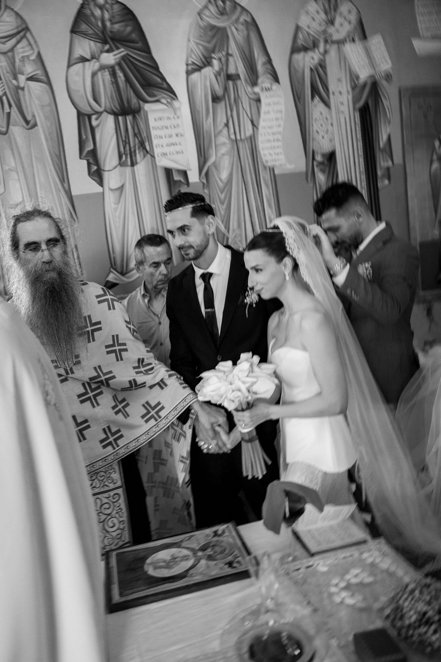 Wedding ceremony inside a church with religious artwork and icons decorating the walls.