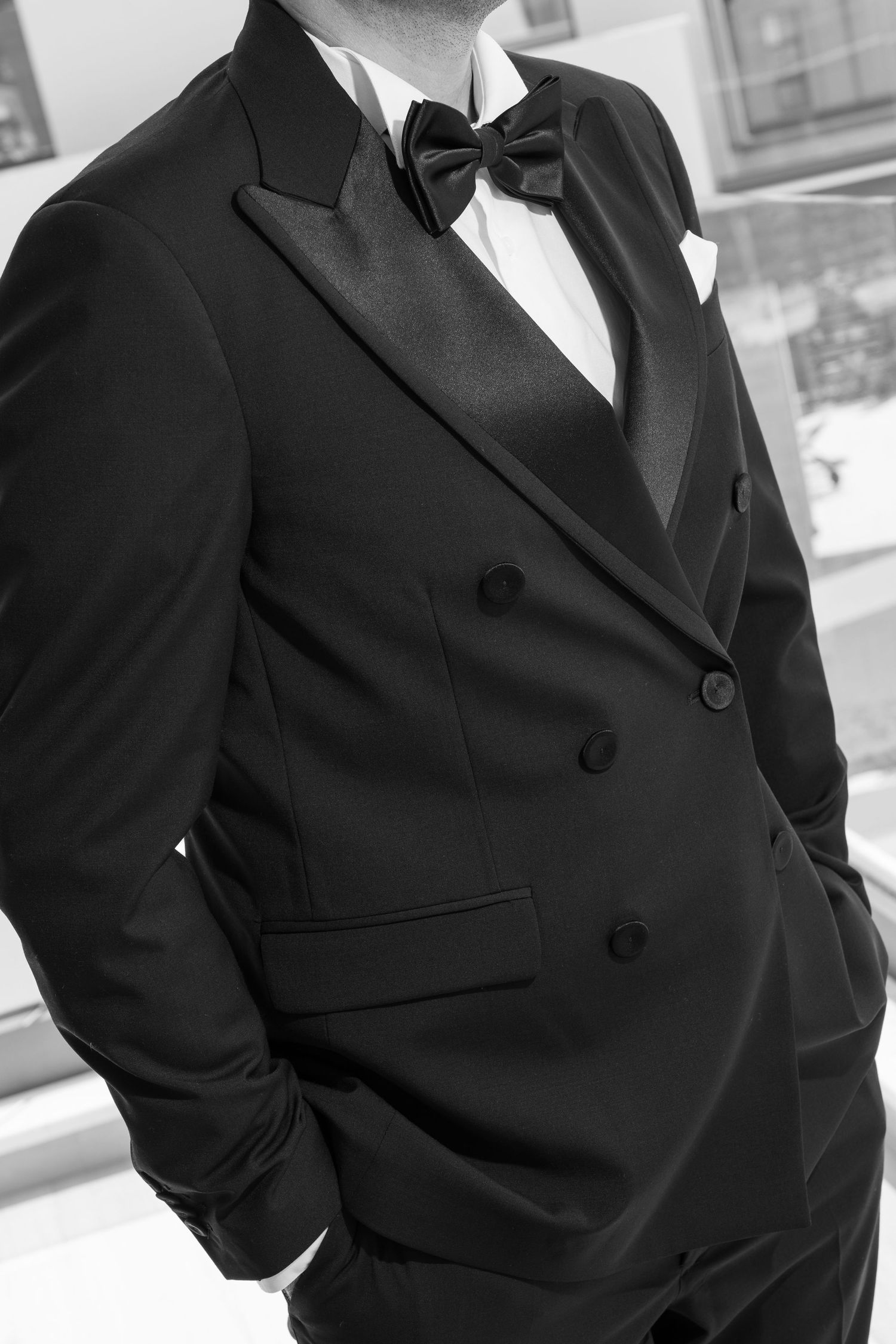 A close-up black and white photo of an elegant tuxedo with bow tie, showing refined formal menswear details.