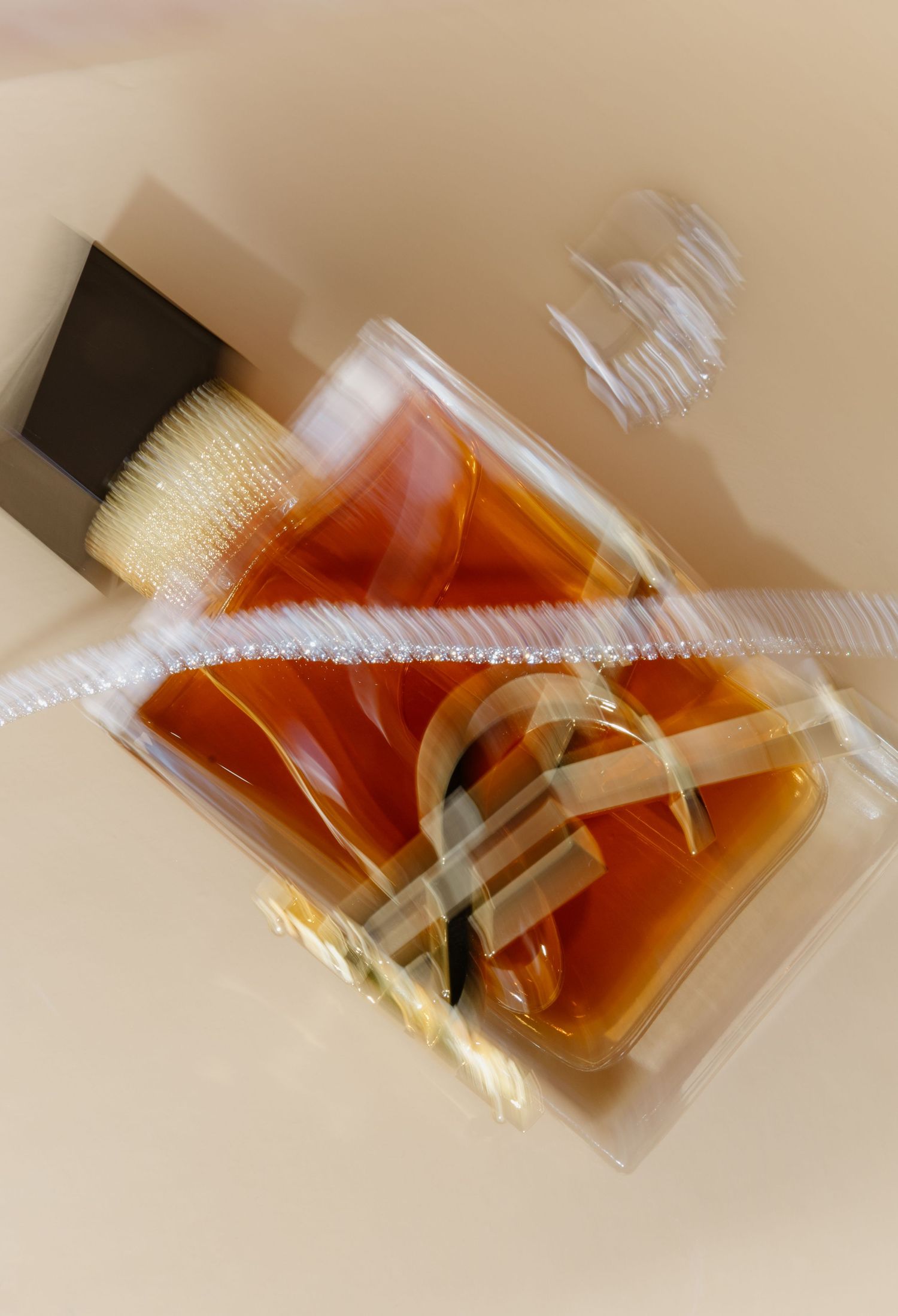 Close-up of an amber glass perfume bottle with gold accents, captured with artistic motion blur effect.