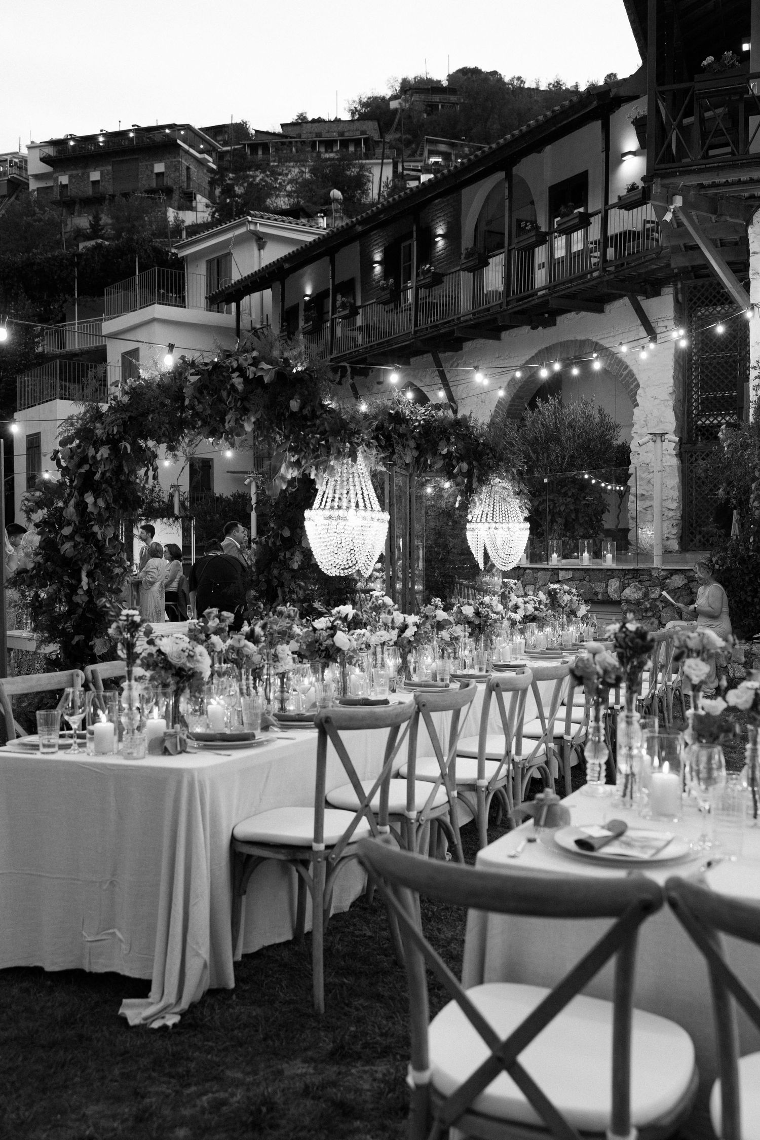 Enchanting outdoor reception venue with crystal chandeliers and mountain villa backdrop.