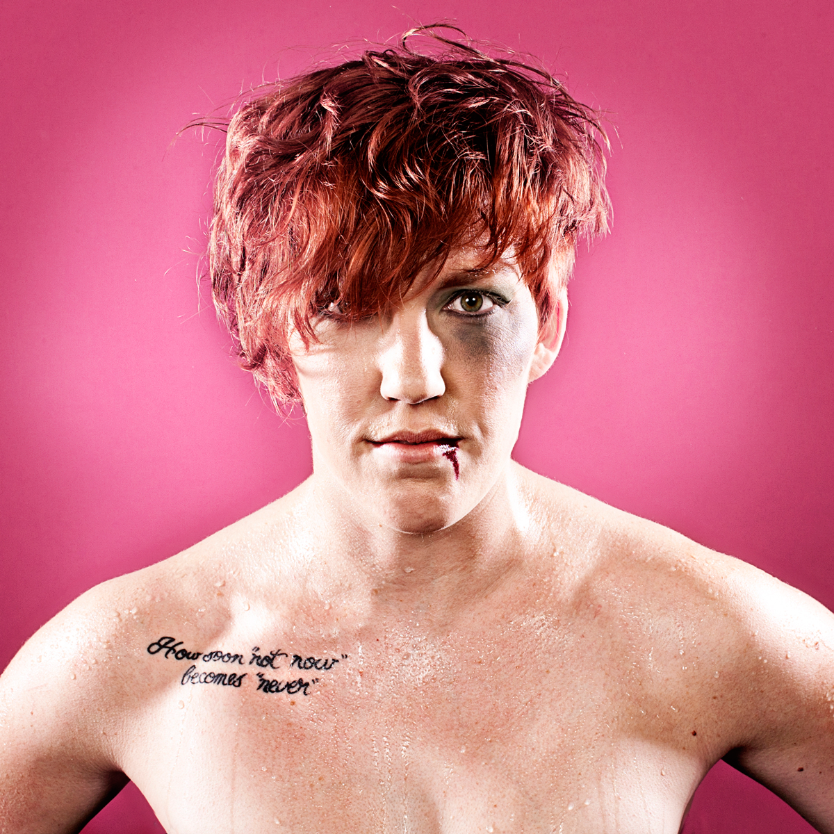 Portrait of person with short red hair against pink background.