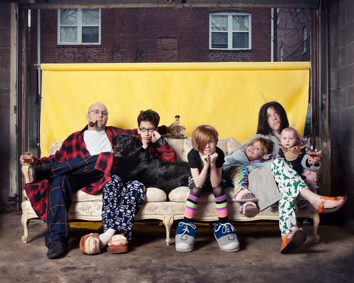 Creative group photo with people lying down against industrial yellow and brown wall.