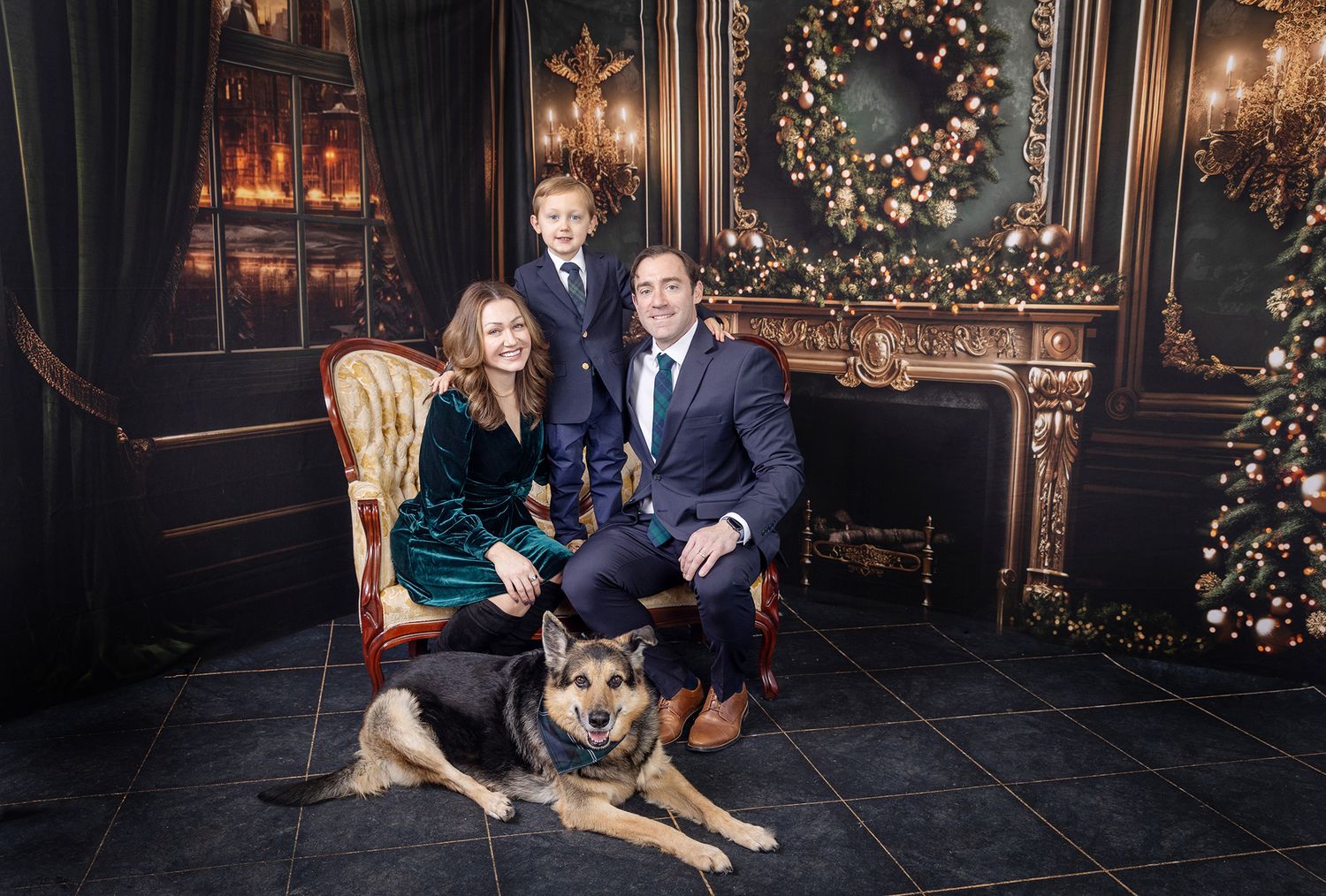 Elegant holiday portrait with a couple sitting in luxurious vintage room with Christmas decor and German Shepherd at their feet.