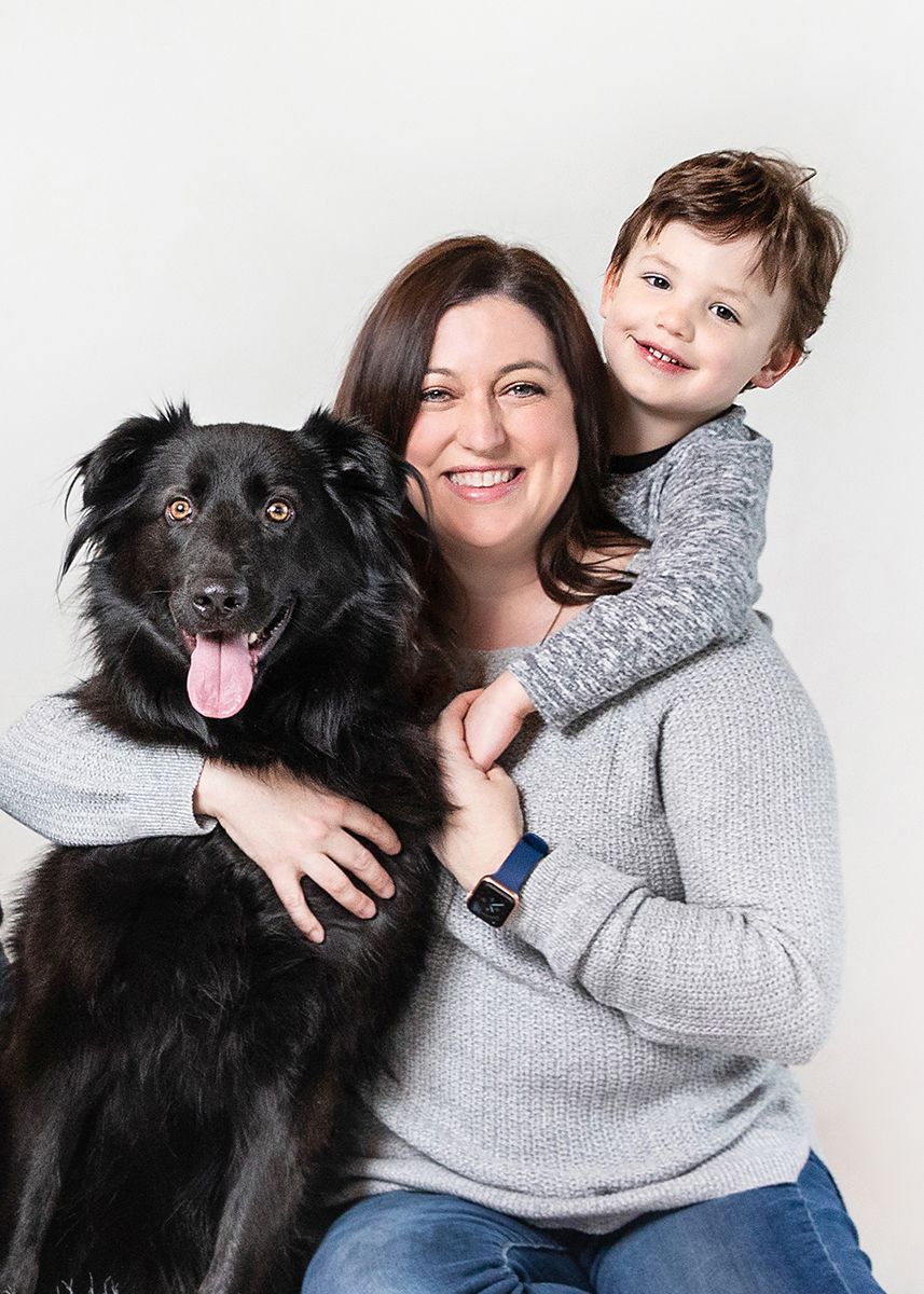 Black fluffy dog posing in studio against white background with holiday decorations.