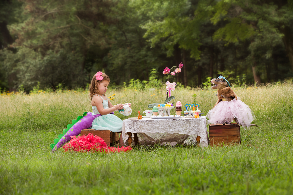 Children enjoying outdoor tea party with fancy decorations in sunny meadow.