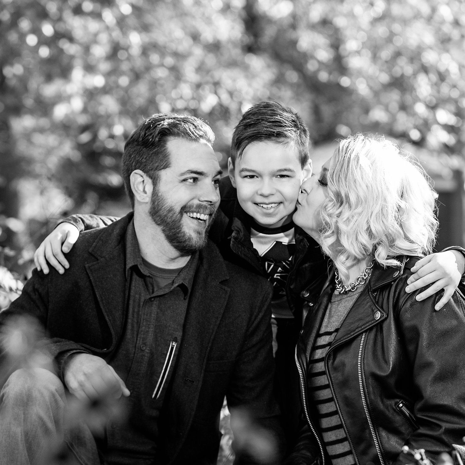 Black and white outdoor family portrait with bokeh background effect.