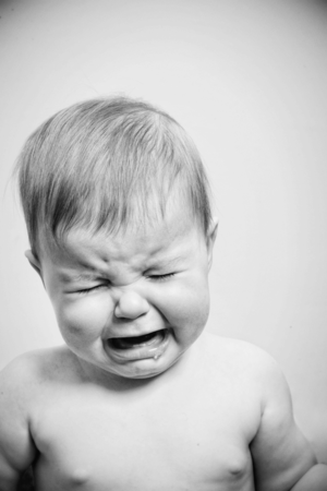 Close-up black and white portrait of a crying baby showing raw emotion.