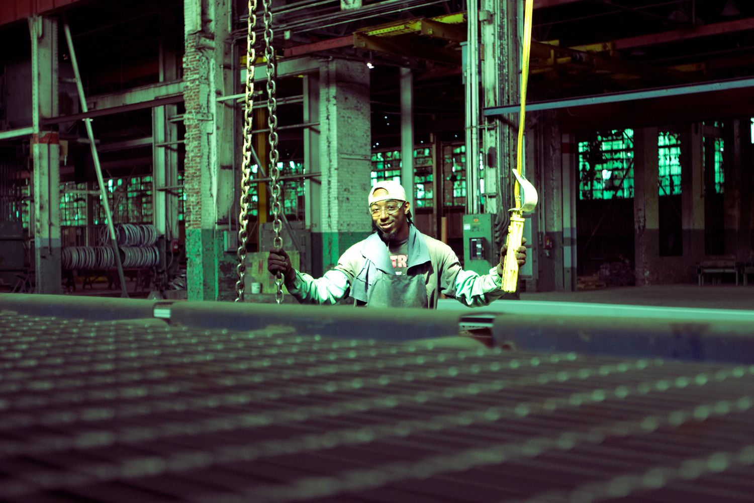 Person in industrial setting illuminated by green lighting and grid pattern.