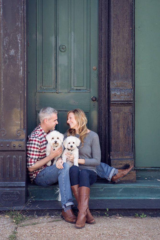 Couple sitting on steps with two white dogs for engagement photos.