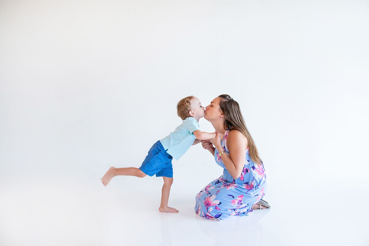 Sweet candid moment with floral dress against white background.