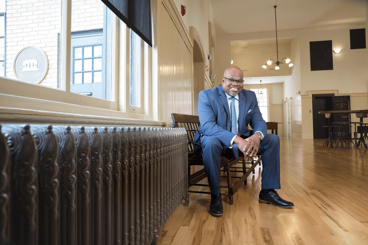 Person sitting on wooden bench in hallway with large vintage radiator.