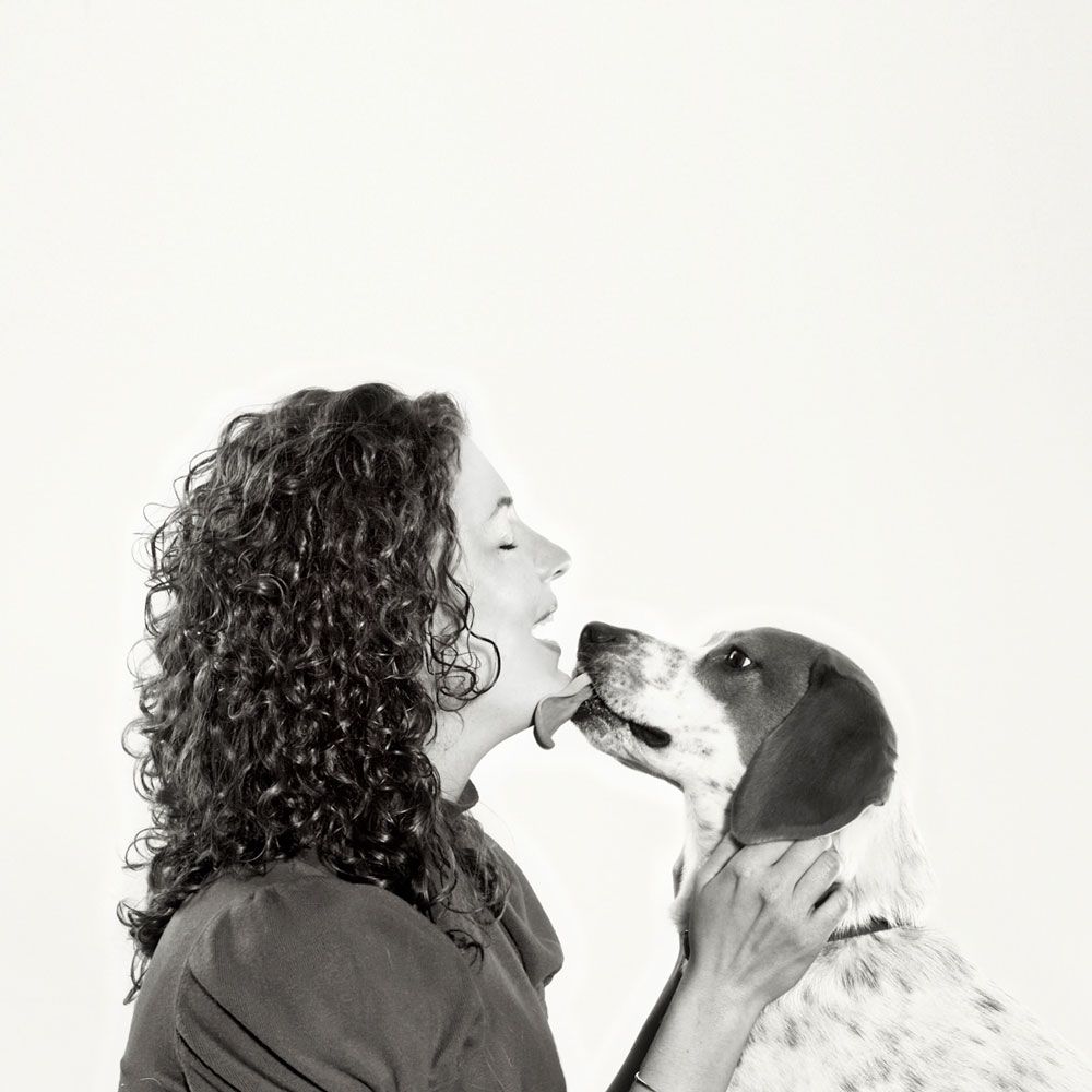 Black and white portrait of affectionate interaction between a person with curly hair and their dog.