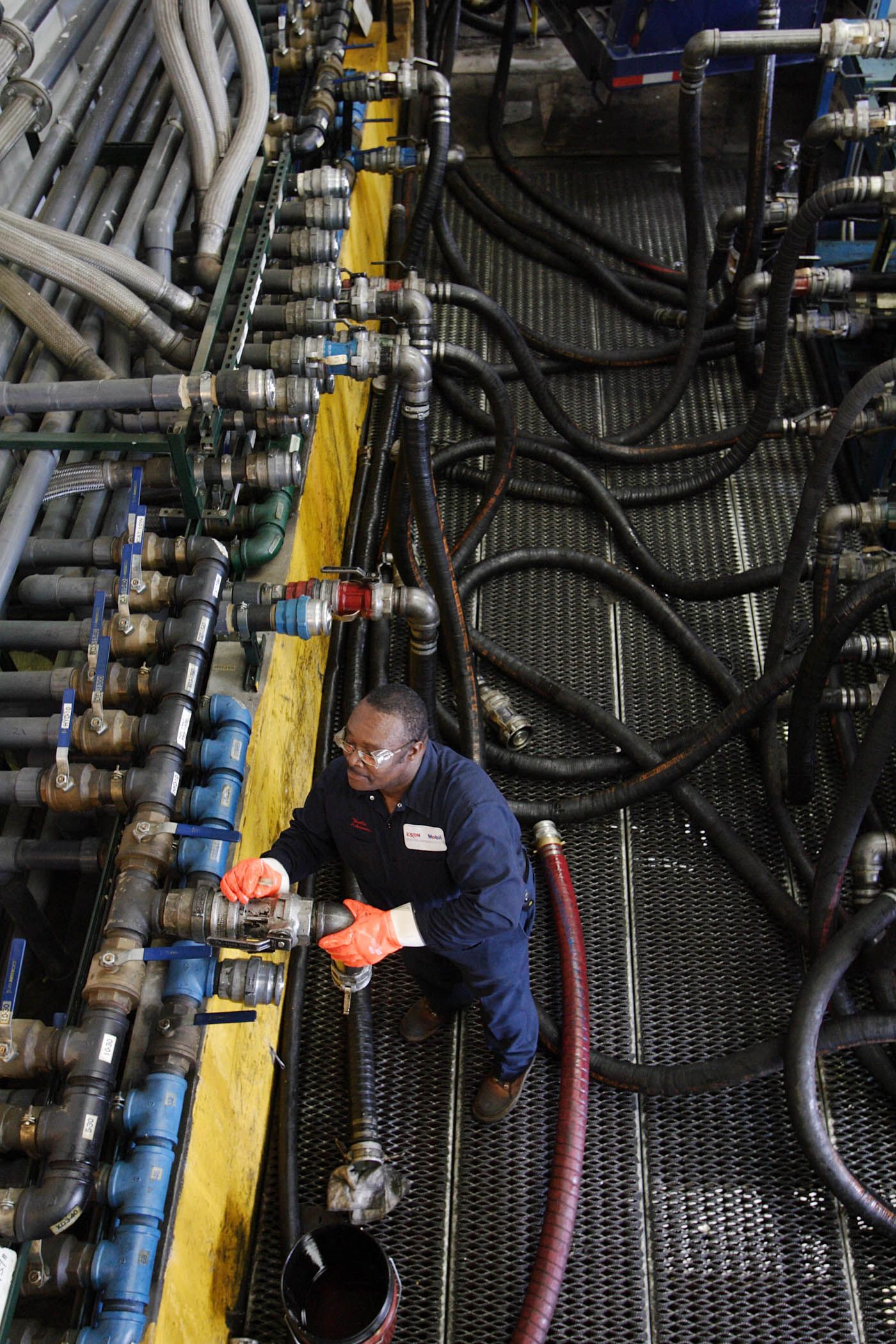Maintenance worker inspecting complex network of industrial pipes and valves.