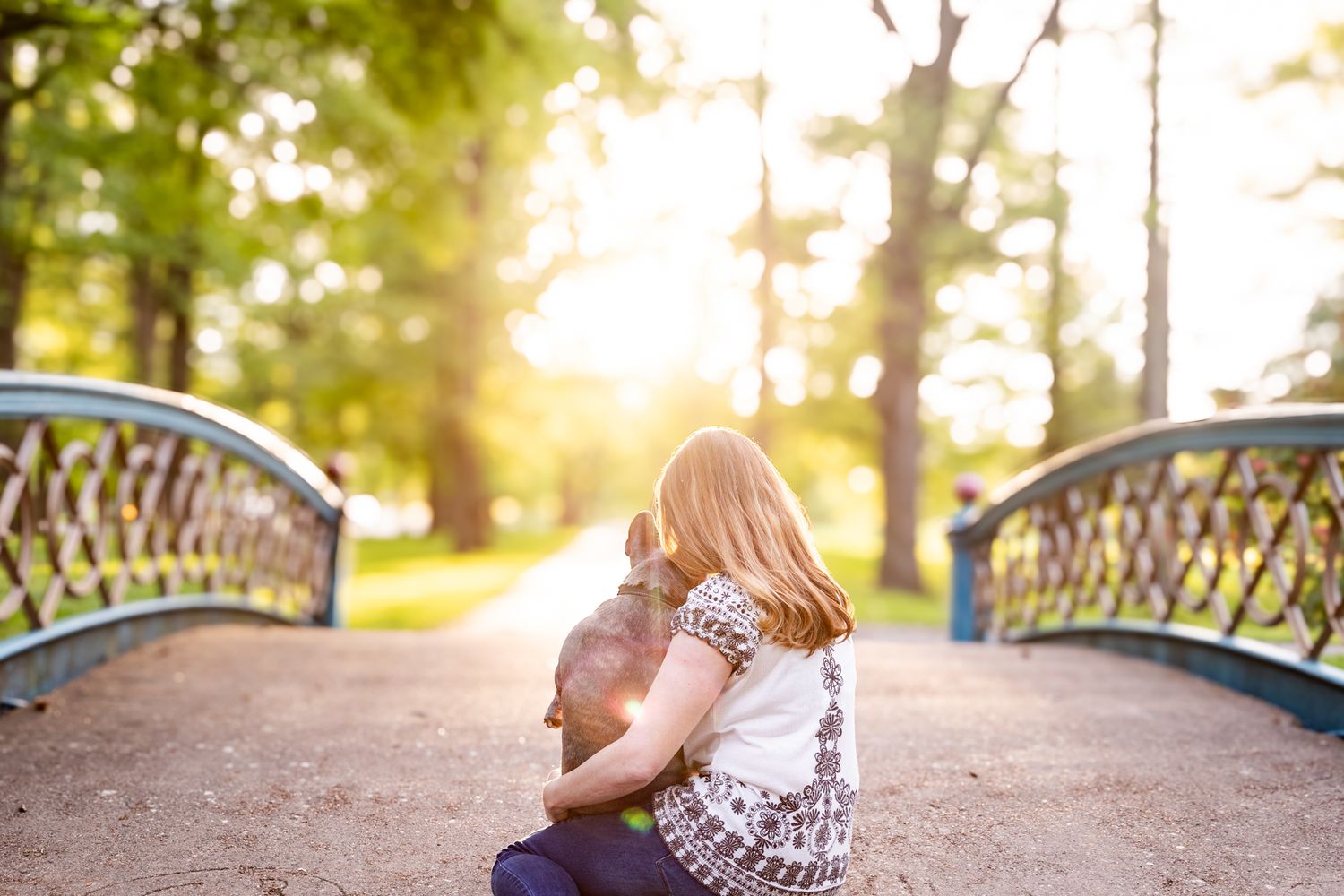 A tender moment captured on a bridge during golden hour in a park setting.