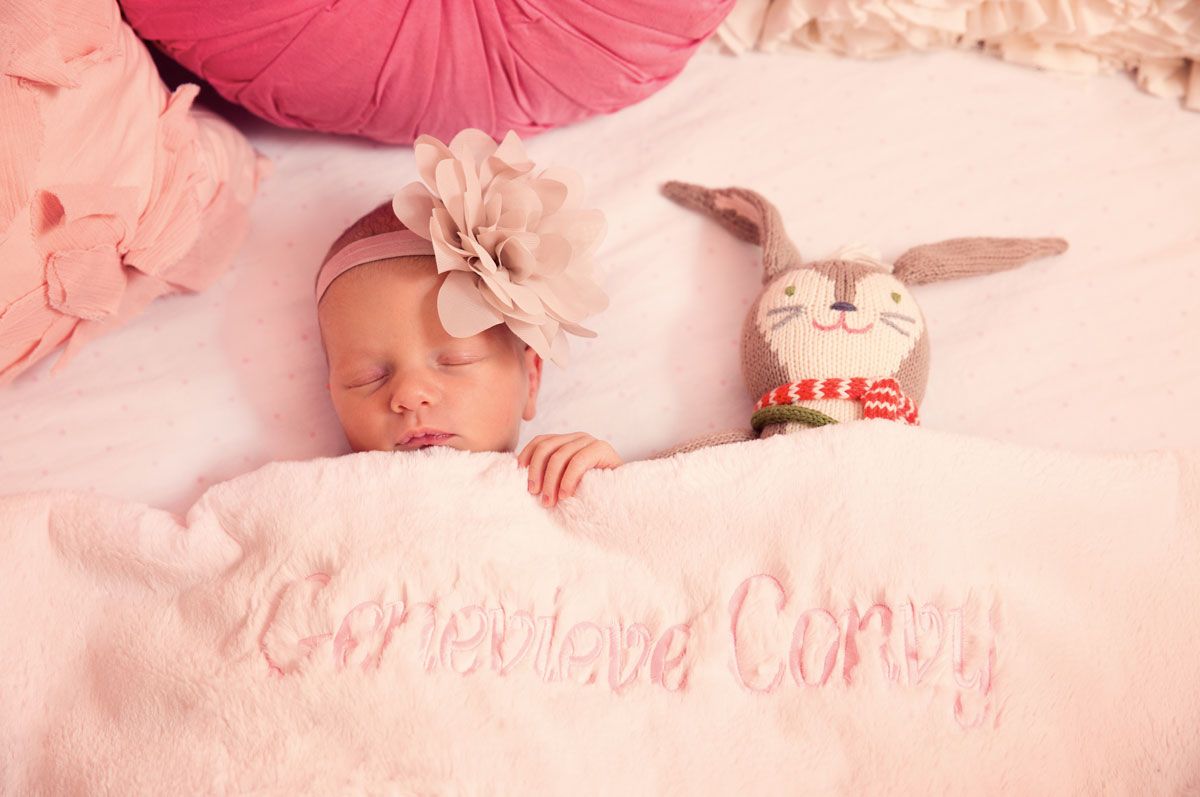 A sleeping baby in pink surroundings captured in a dreamy photography style.