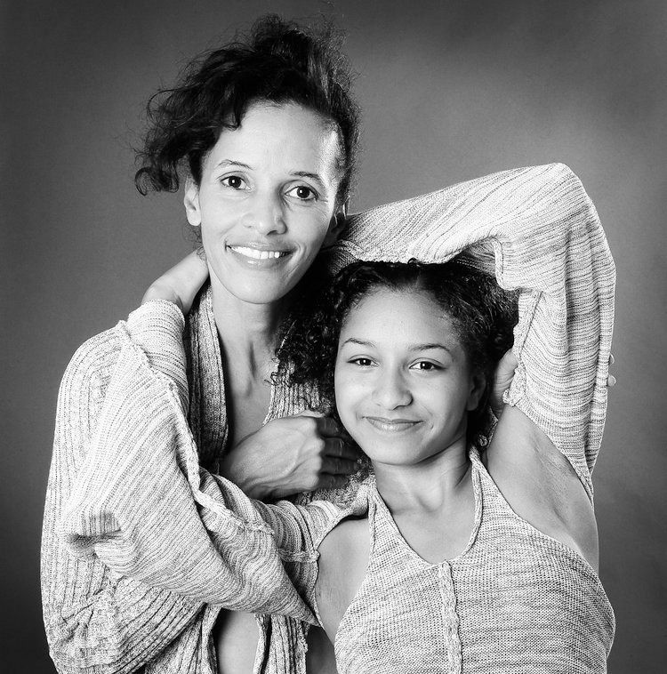 Black and white portrait of two people embracing and smiling at camera.