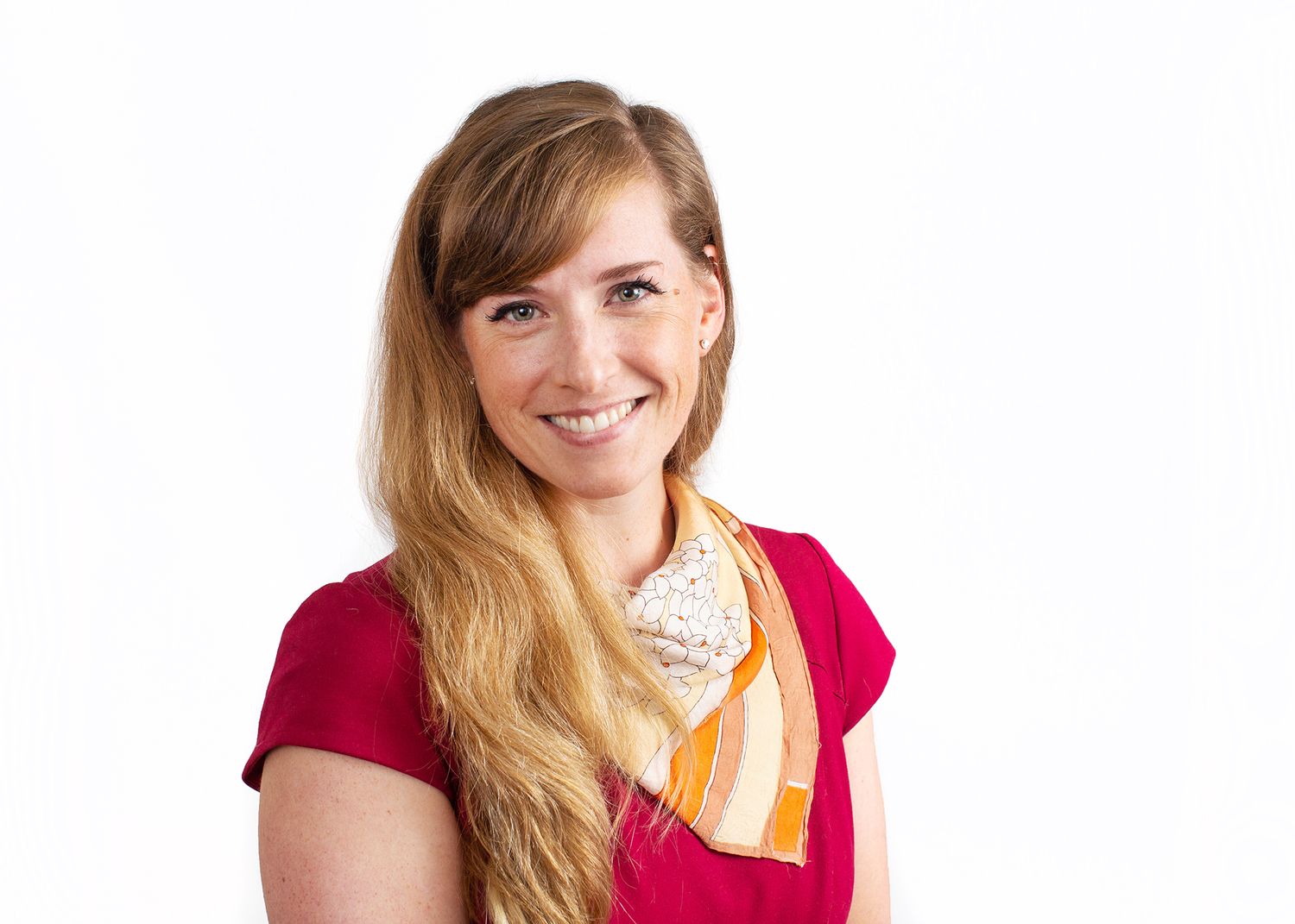 Professional portrait in bright red top against white background.