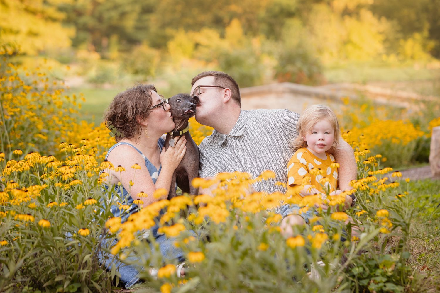 Family enjoying a candid moment together in a field of bright yellow wildflowers.