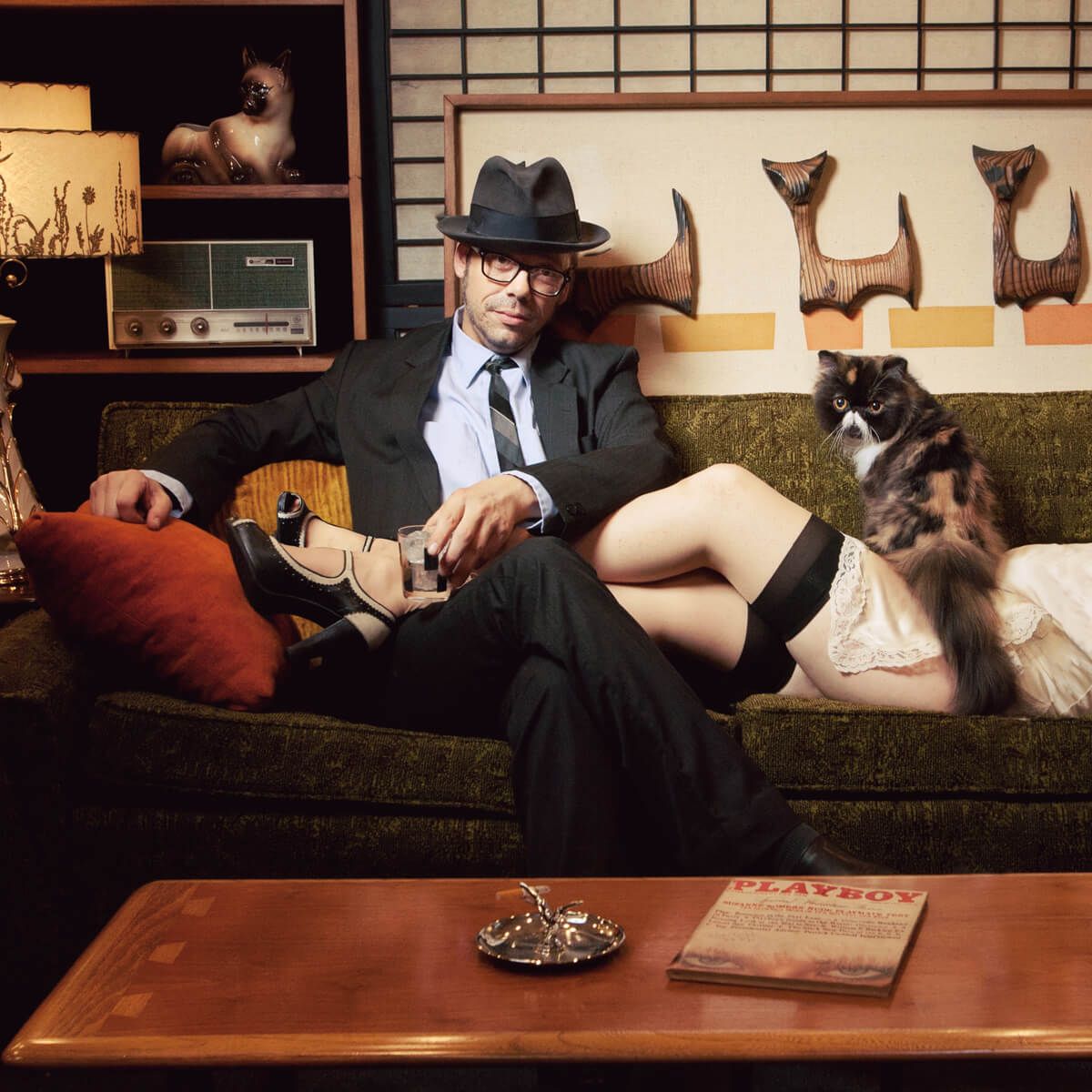 Retro-style photo of someone relaxing on a couch with dogs while dressed in business attire.