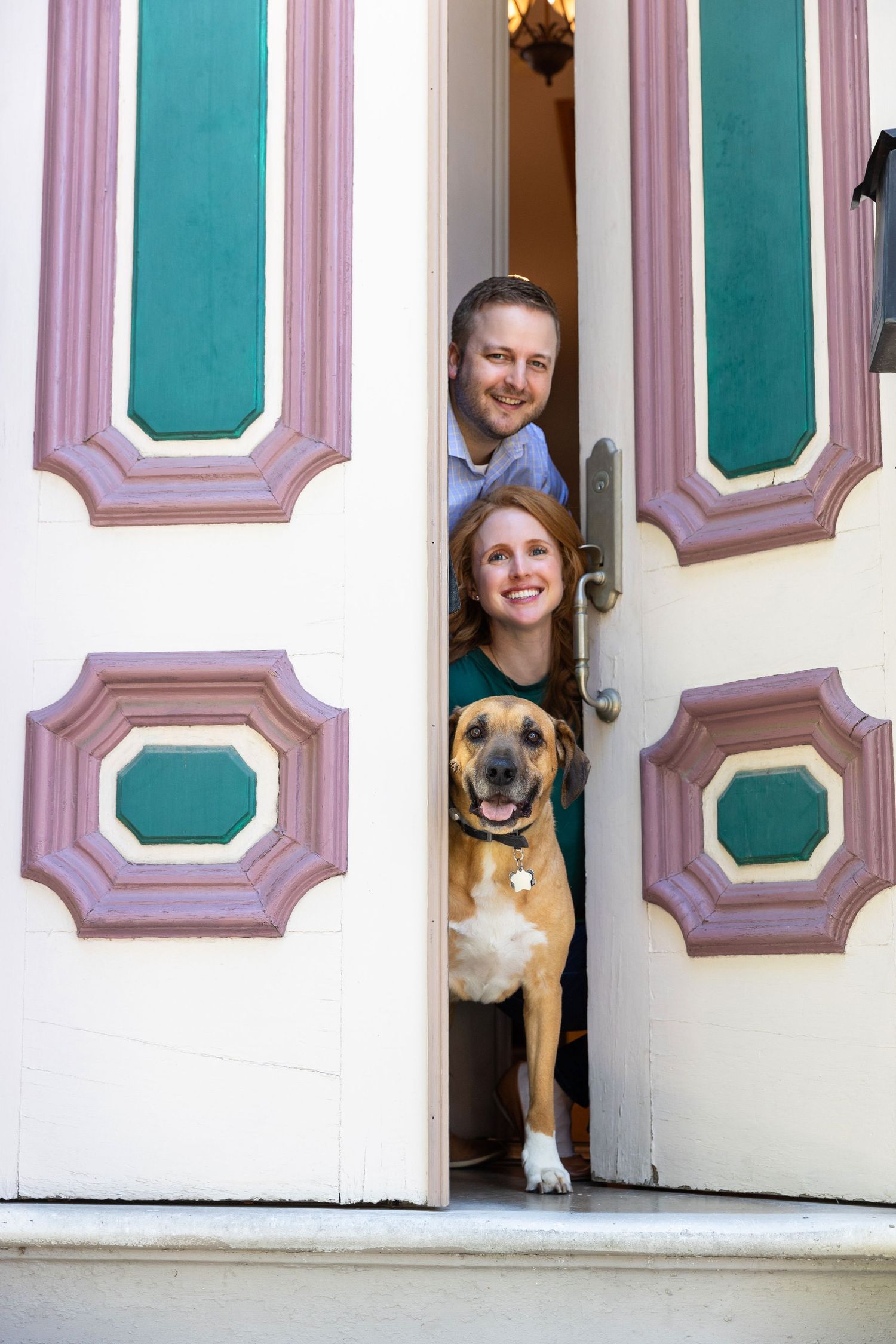 Playful portrait through partially open decorative door with dog peeking out.
