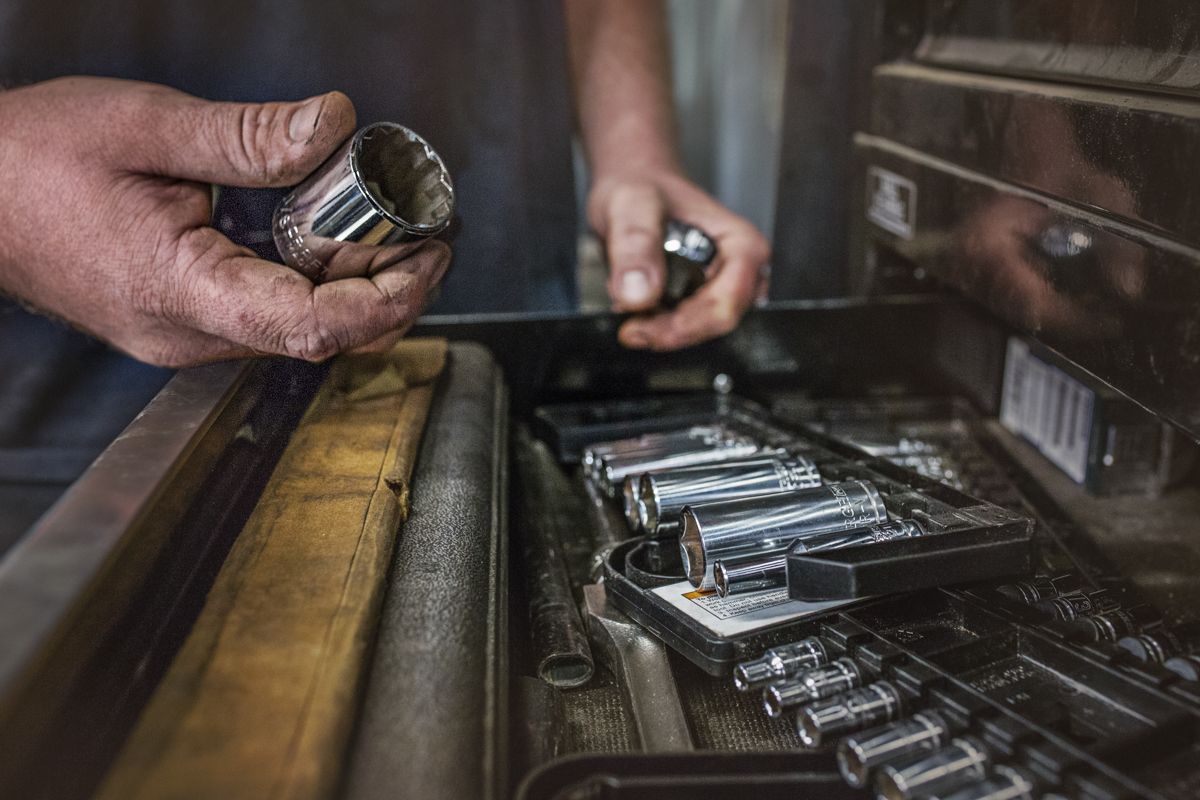 Close up of hands working on vintage letterpress machinery with metal type.