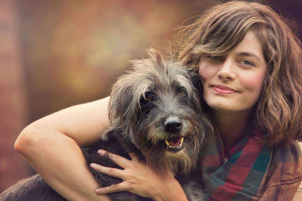 Sweet outdoor portrait of a scruffy grey terrier mix dog and owner sharing an affectionate moment.