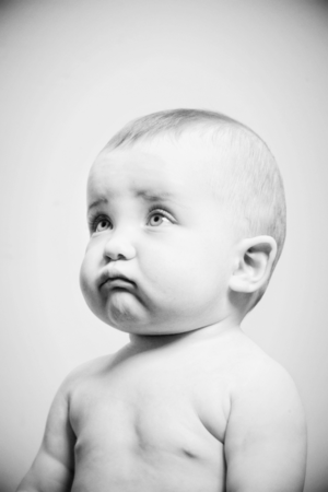 Black and white portrait of baby looking up with contemplative expression.