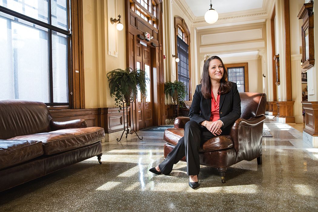 A professional sits in a leather chair in an elegant hallway with natural lighting.
