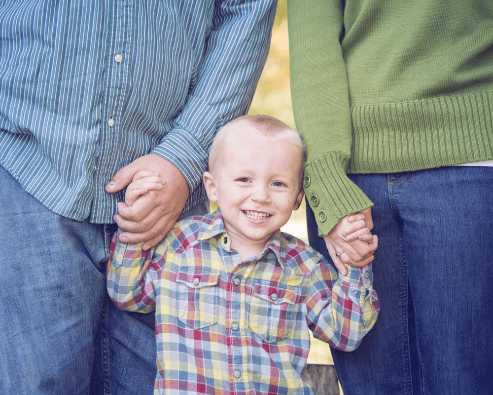 A delightful family moment with parents holding hands with their child outdoors.